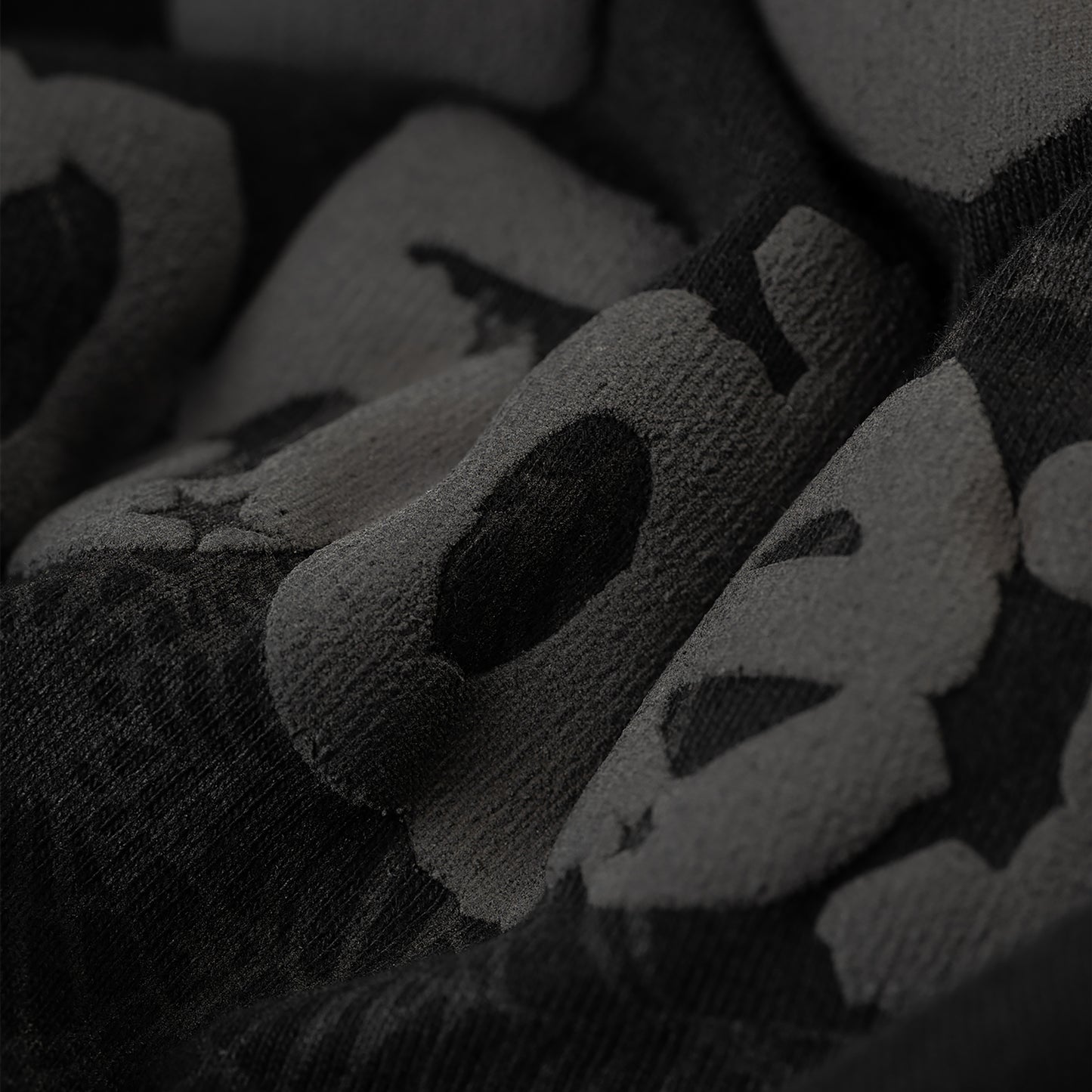 Close-up of a black Phantom Souvenir Men's Tee with subtle dark gray textured lettering.