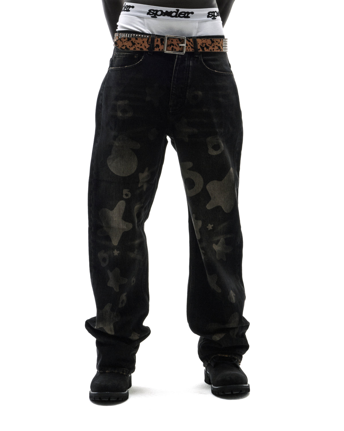 Model wearing black baggy jeans with subtle star and number prints, a leopard print belt, and black boots.