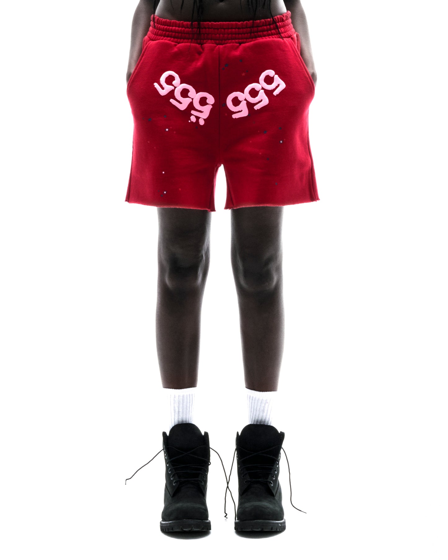 Model wearing red 100% cotton fleece shorts with pink "555" angel numbers and scattered stars.