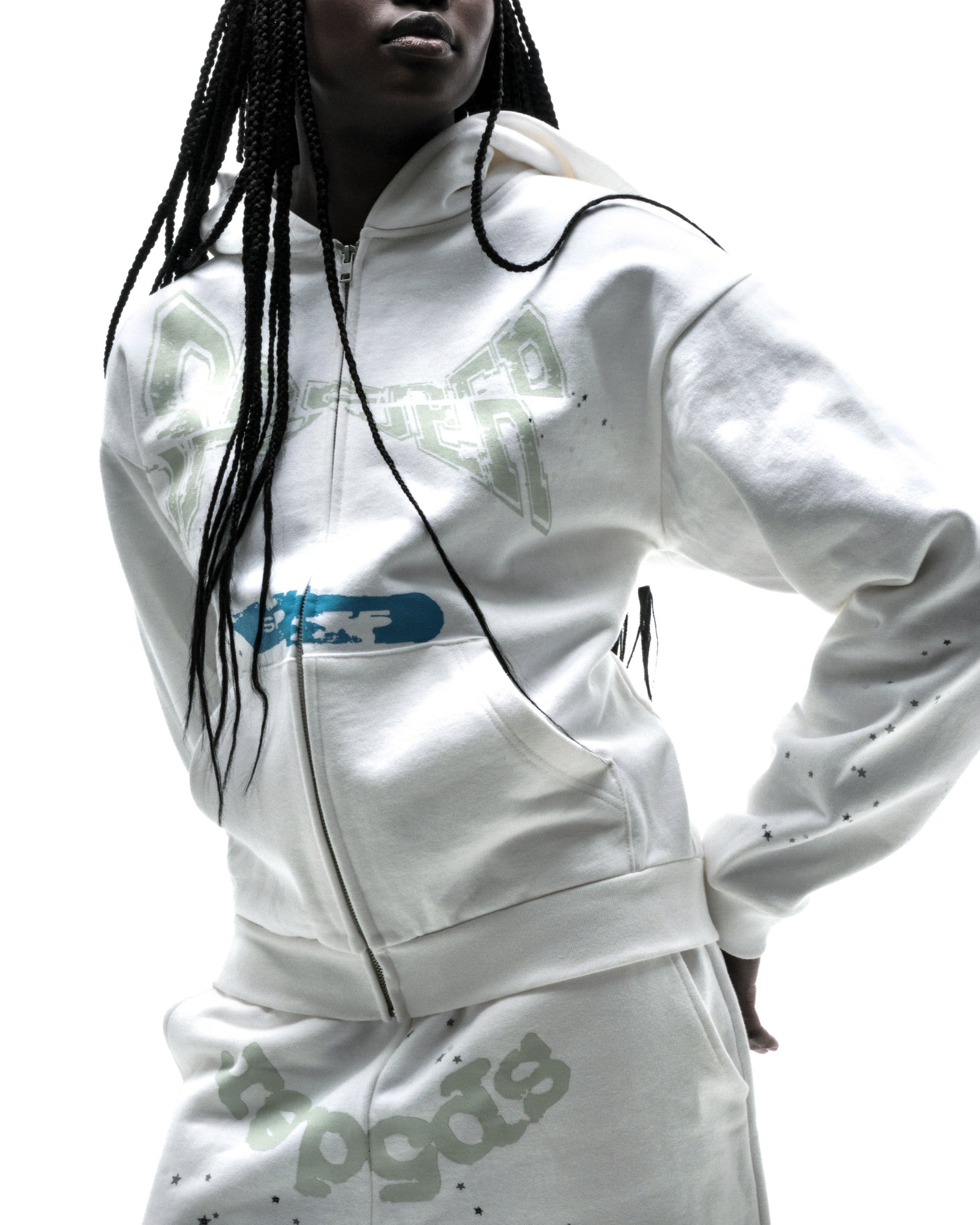 Model in white 13oz cotton fleece T&F zip-up hoodie with puff print and scattered stars.