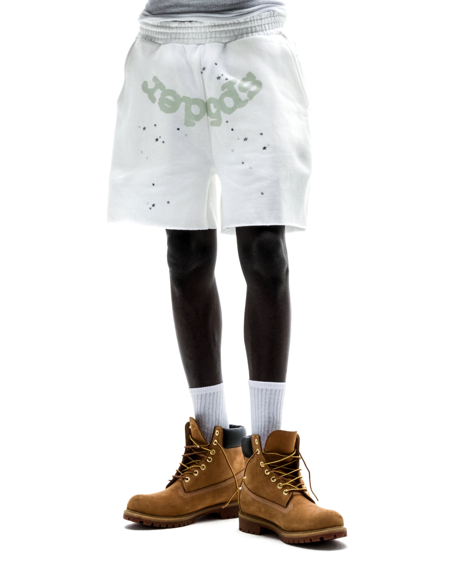 Model wears white T&F SWEATSHORT with "SP5DER" print, scattered stars, raw hem, and drawcord.