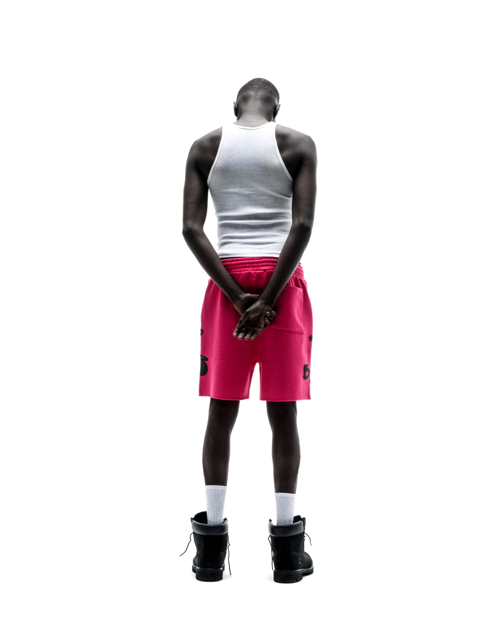 Model from behind wearing pink Beluga sweatshorts with black print, raw hem, and drawcord.