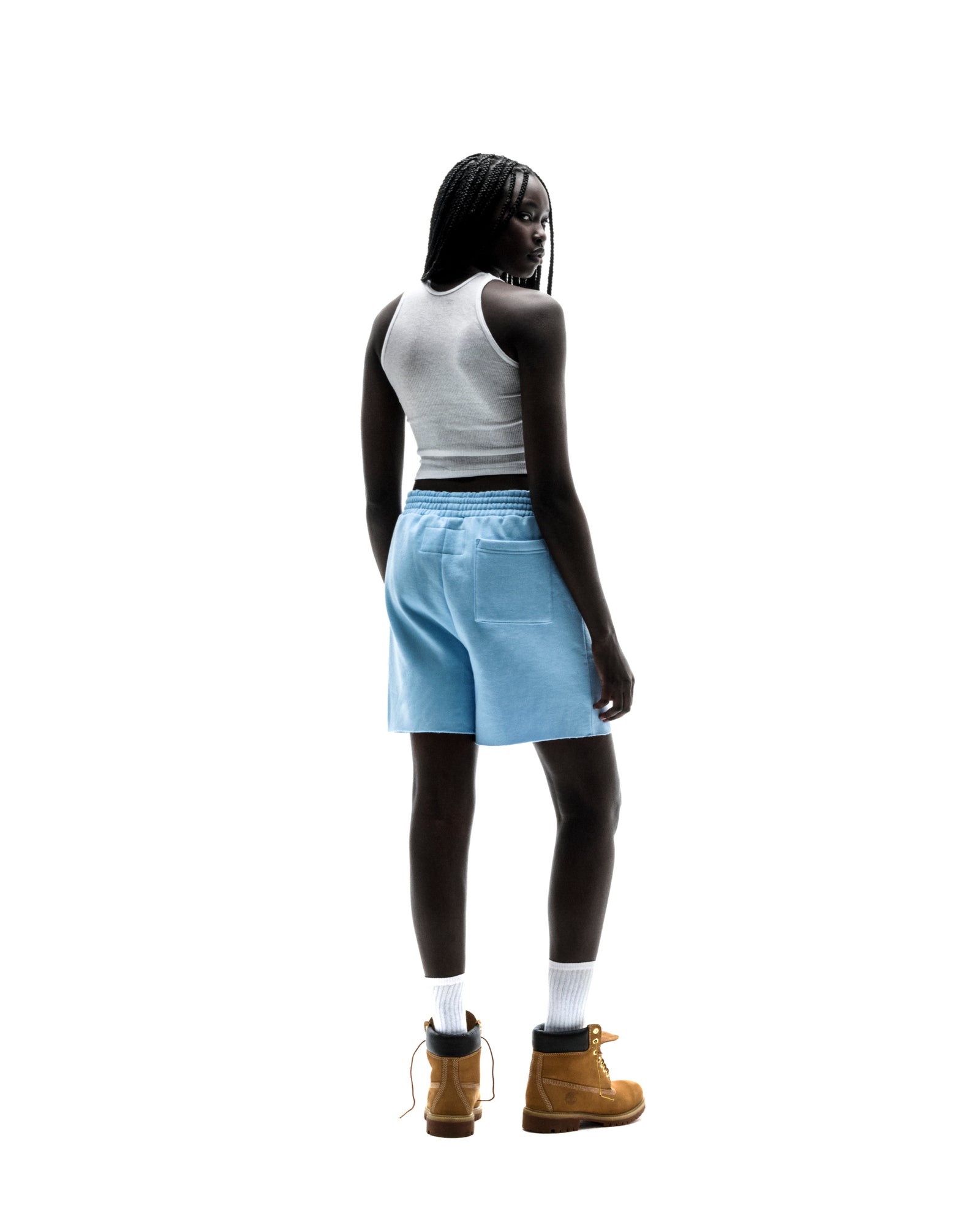 Model in light blue OG WEB SWEATSHORTS with raw hem, back pocket, and "SP5DER" text.