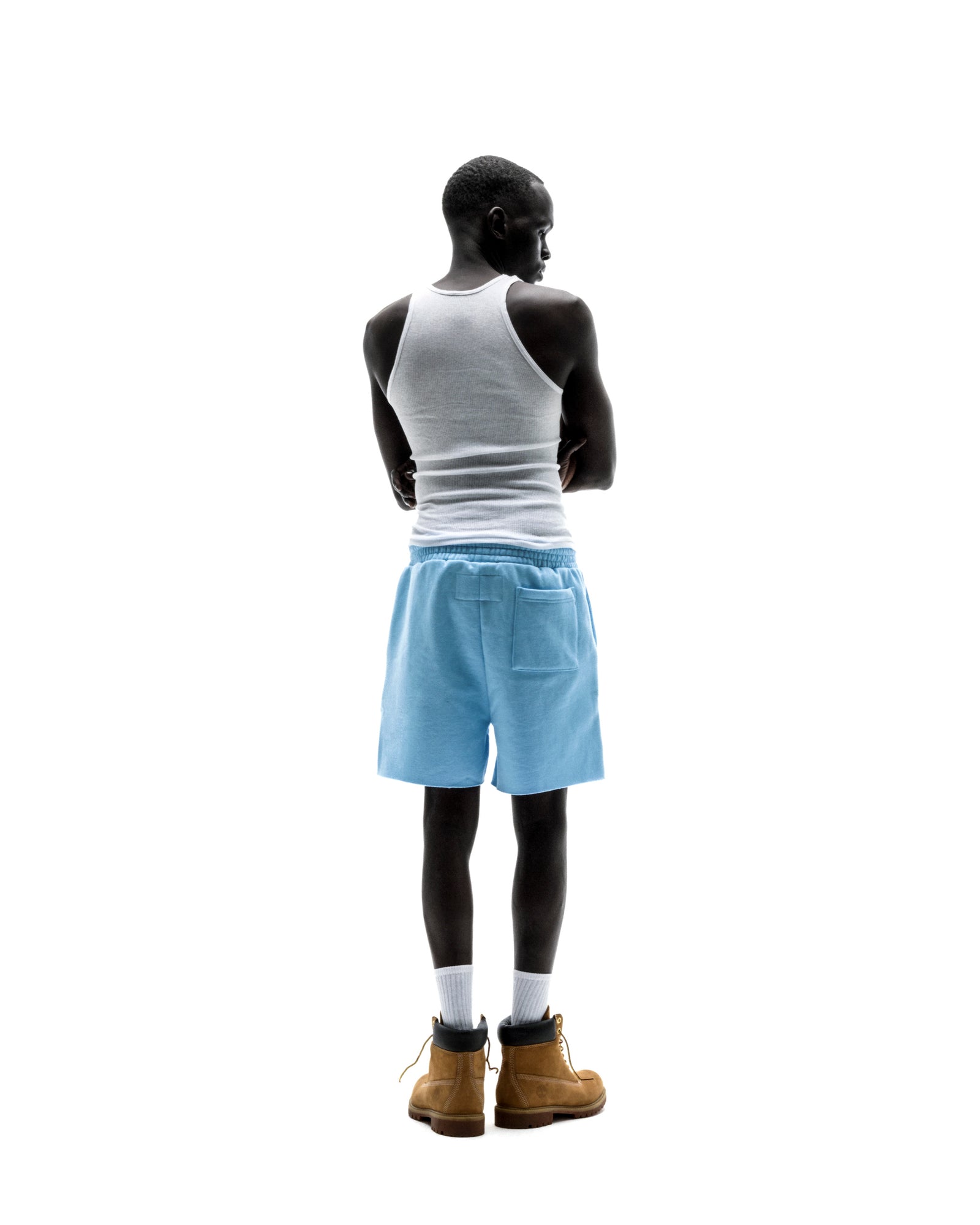 Model wearing light blue OG WEB SWEATSHORTS with back patch pocket, white tank top, and tan boots.