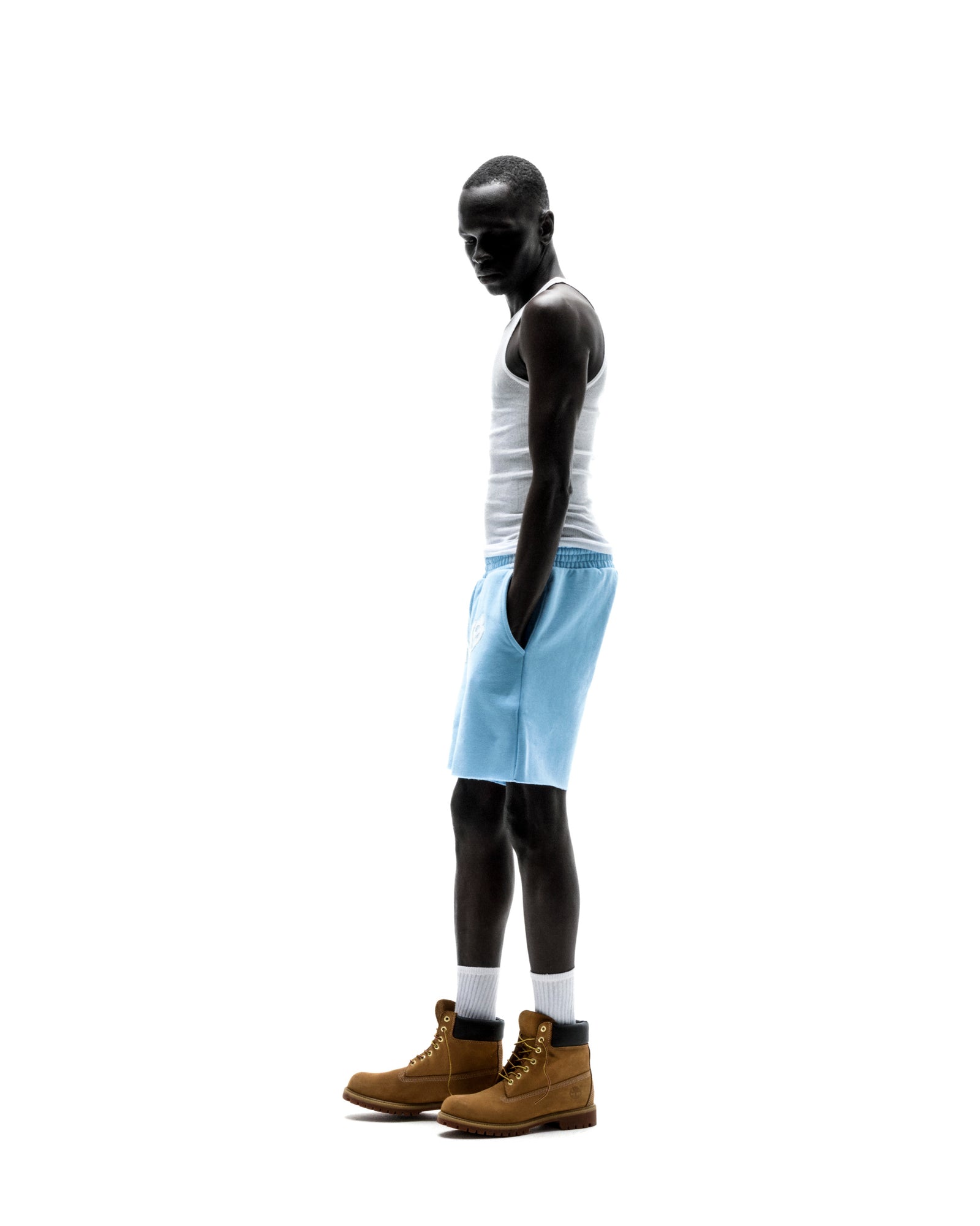 Model wears light blue OG WEB SWEATSHORT with "SP5DER" text, raw hem, and drawcord waistband.