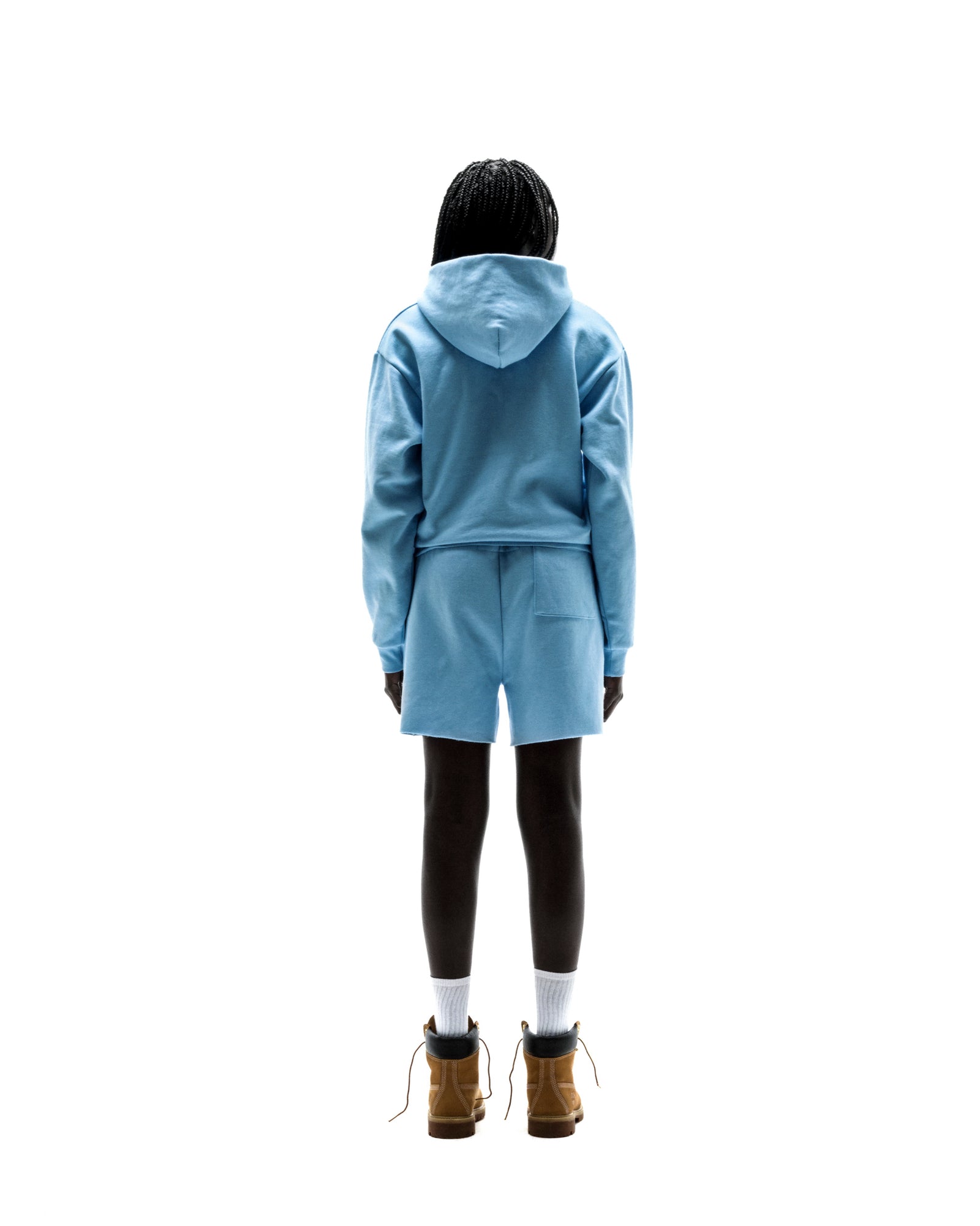 Model from behind in a light blue 13oz cotton fleece zip-up hoodie and matching shorts.