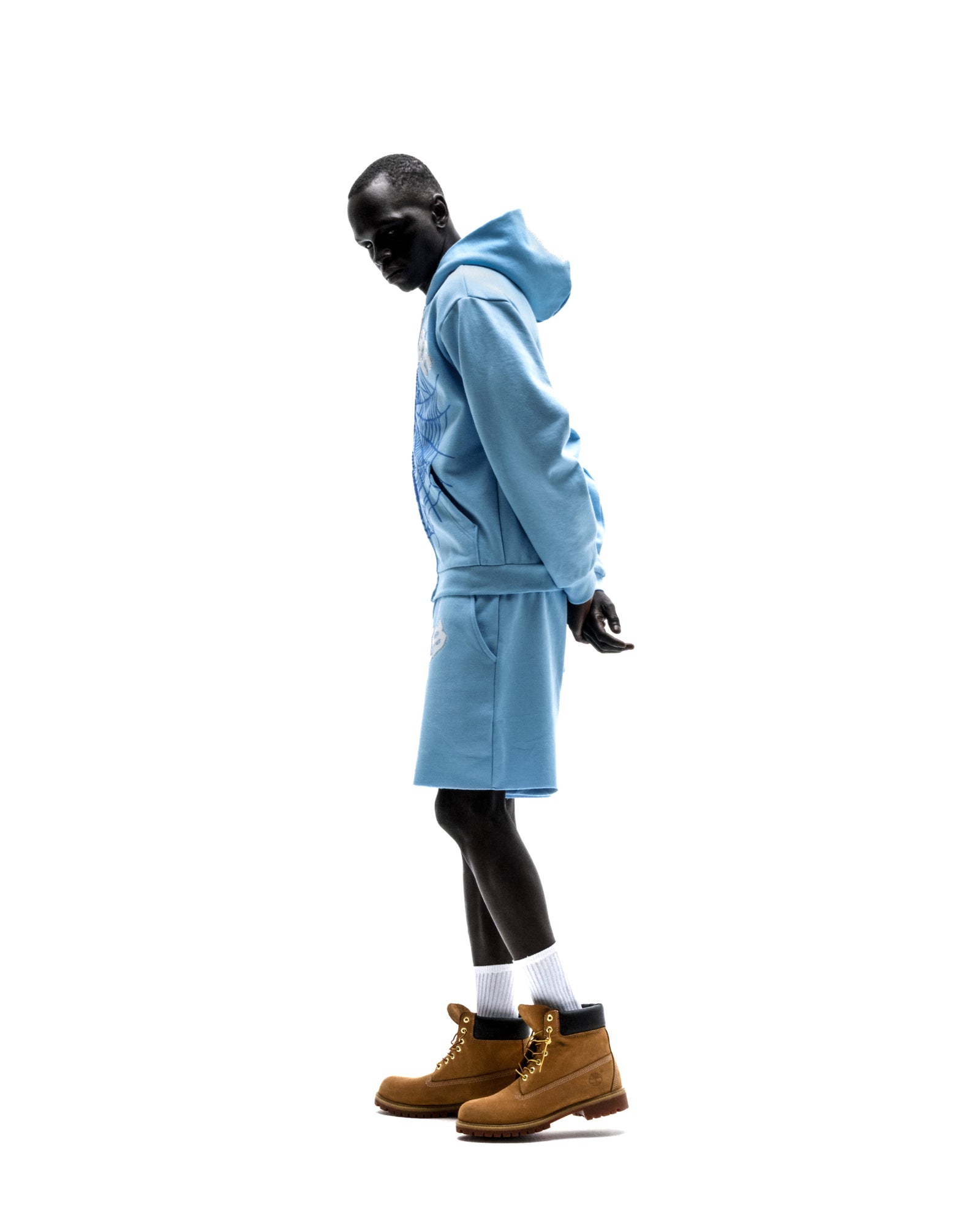 Model in light blue 13oz cotton fleece OG Web Zip Up hoodie and matching shorts, with puff print design.