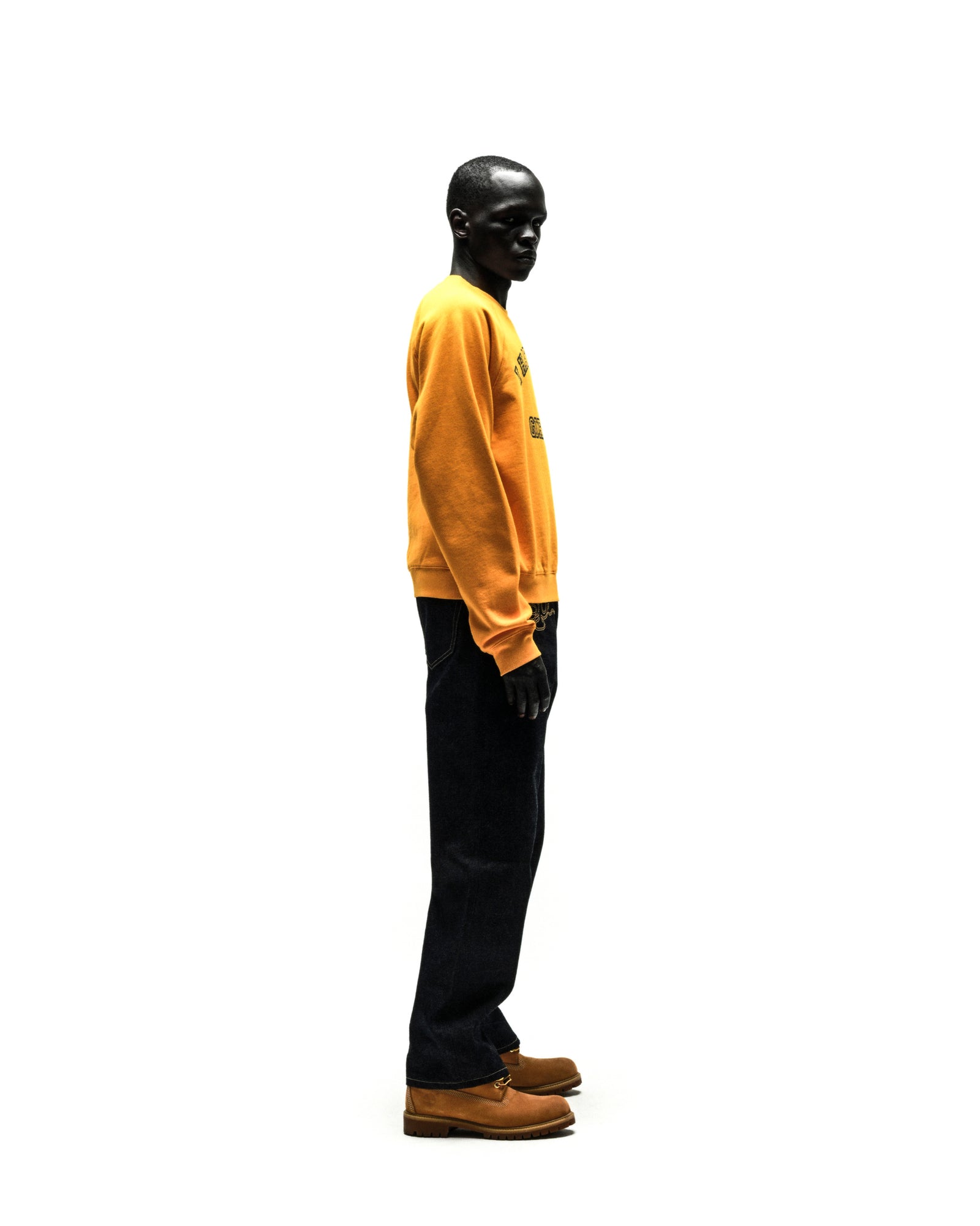 Model wearing a mustard yellow 100% cotton brushed fleece raglan crewneck with a black graphic print on the front.