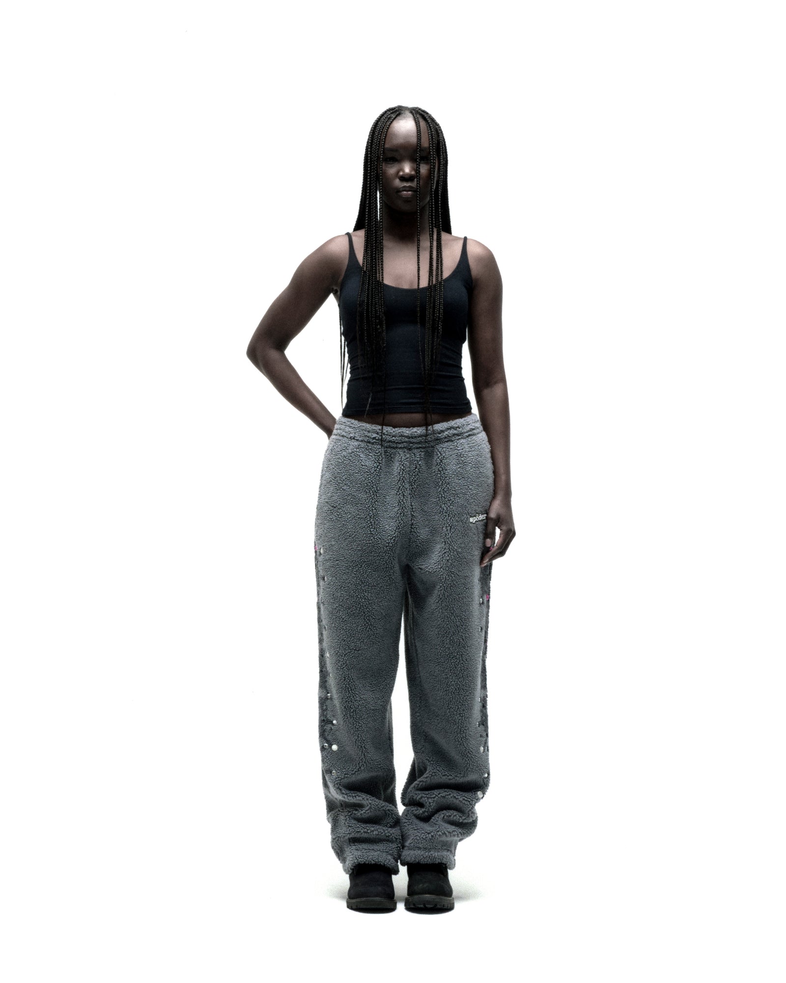 Gray sherpa fleece pants with rubberized logo patch, web print, and rhinestone embellishments down legs.
