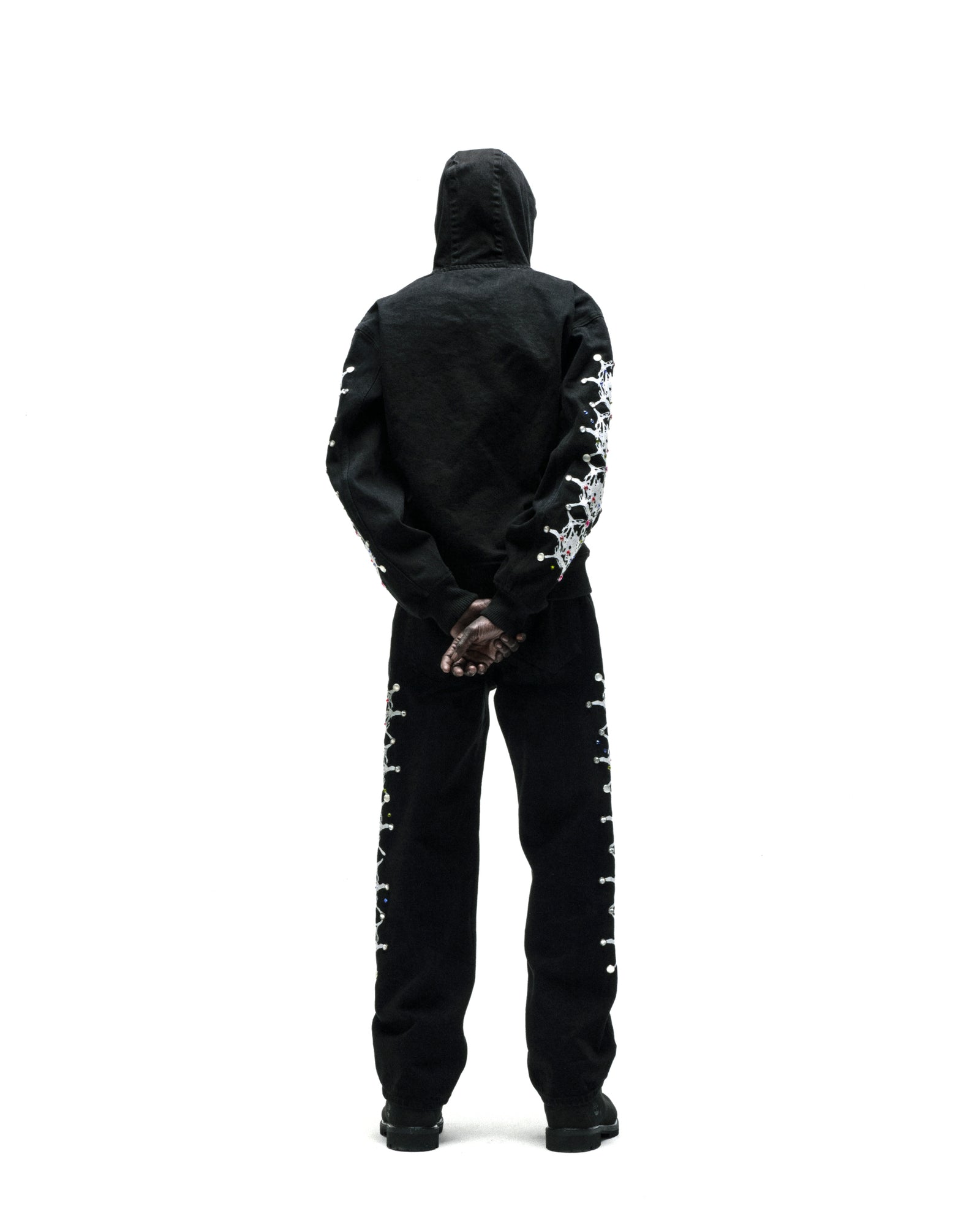Black cotton canvas hooded jacket with web print and rhinestone sleeves, paired with matching pants.
