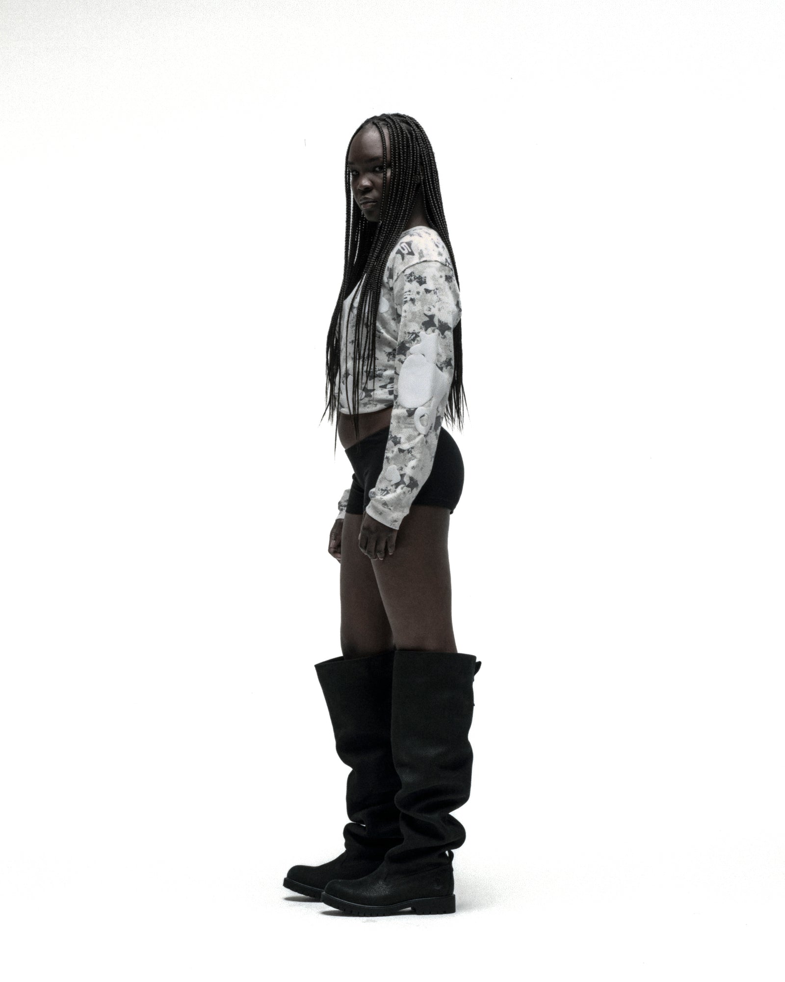 Woman in white star camo waffle knit thermal with Beluga print, black shorts, and tall black boots.