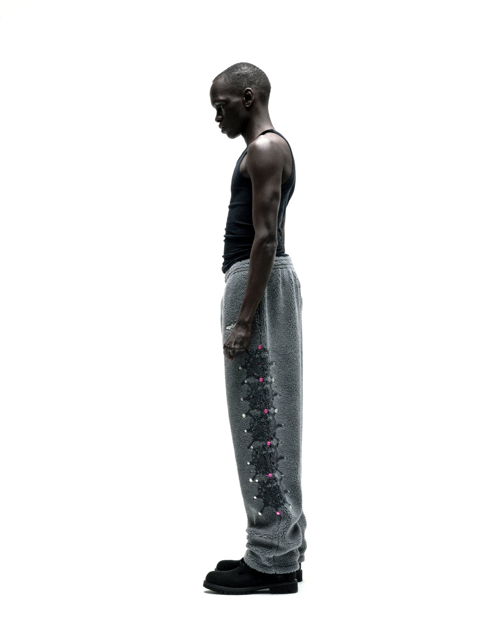 Gray sherpa fleece pants with web print, pink rhinestones, and rubberized logo patch on a model.