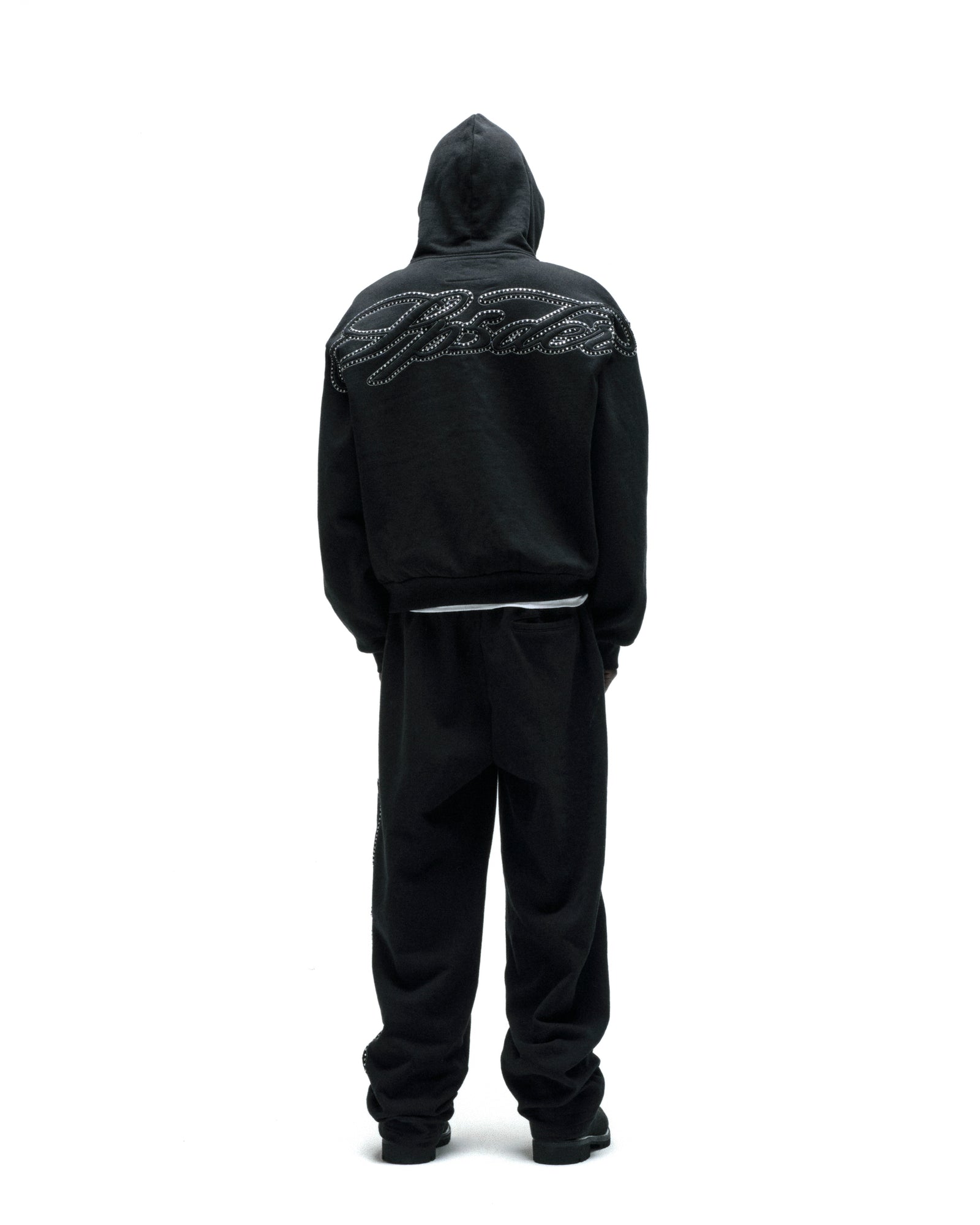 Black 13oz cotton fleece zip hoodie with rhinestone script on the back, paired with matching sweatpants.