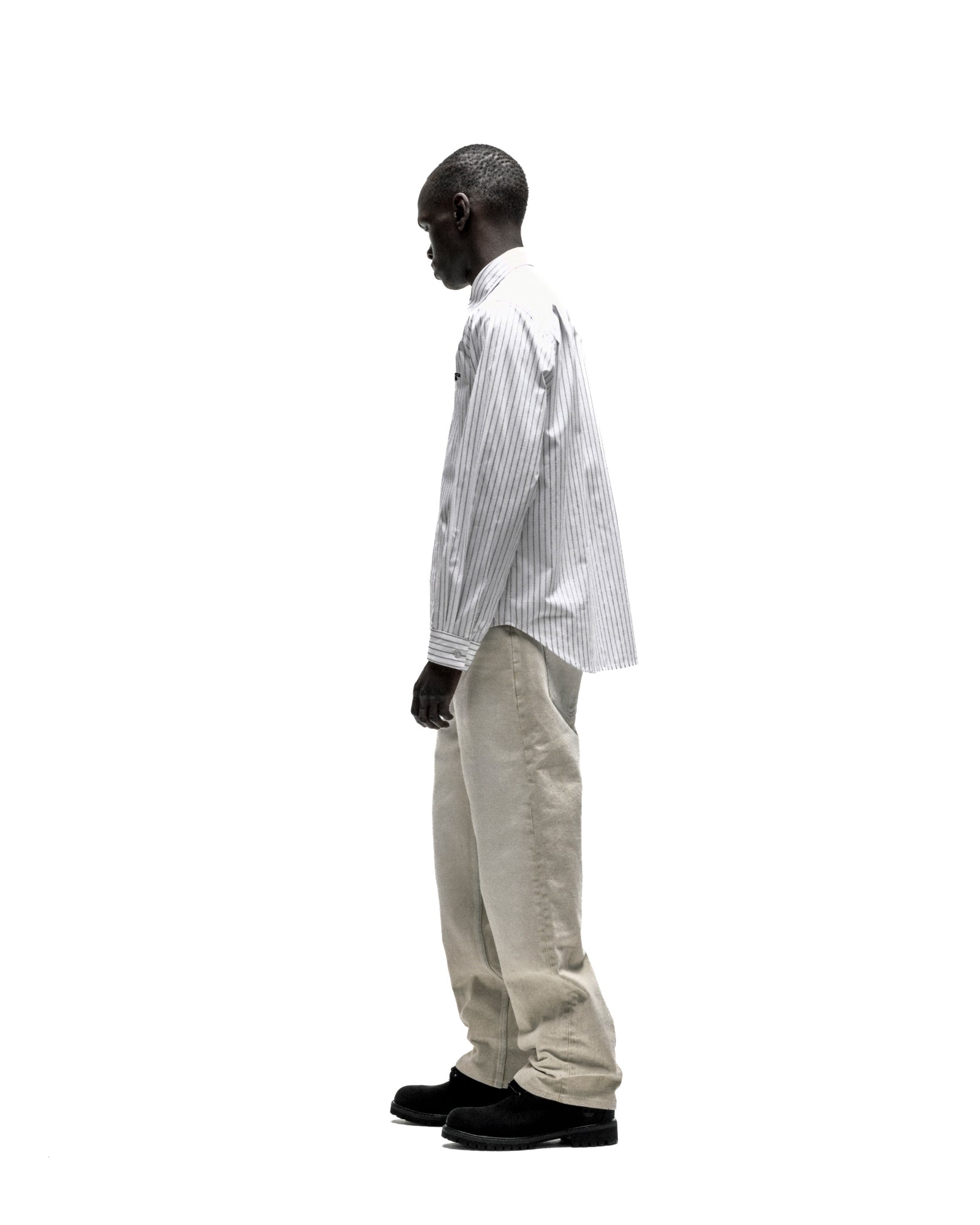 Man in R-05 Oxford Button Down: white woven cotton shirt with 5 pinstripes, embroidered logo, spread collar.