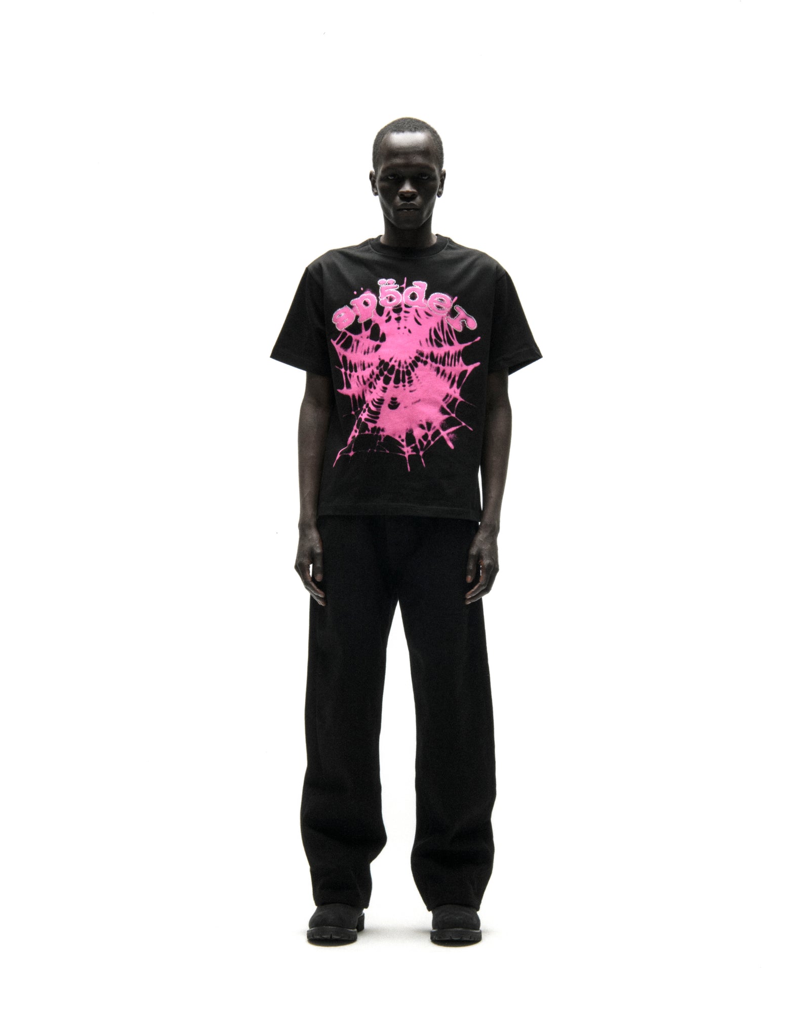 Black cotton tee with pink "SP5DER" text and spiderweb graphic, worn by a male model.
