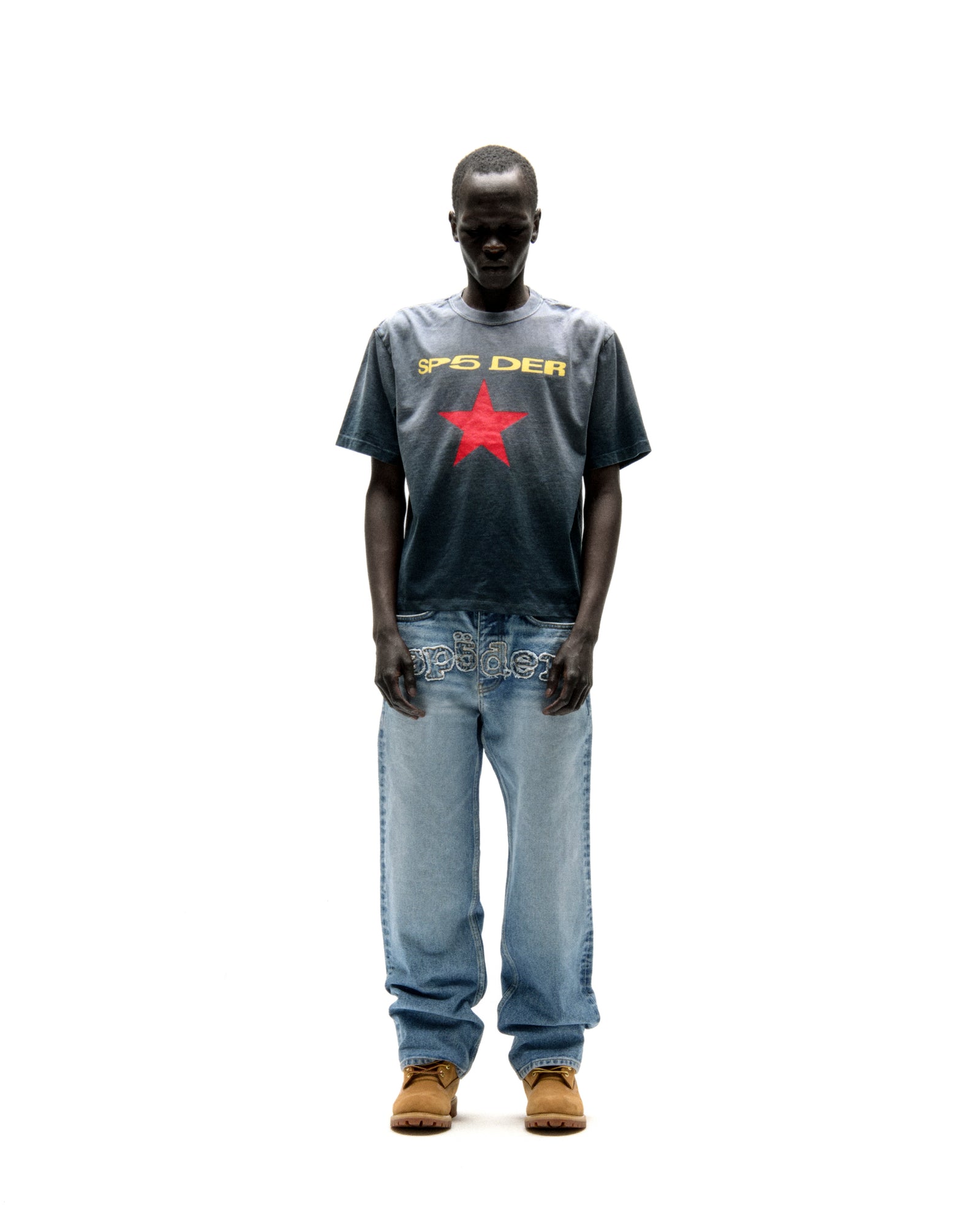 Faded wash cotton tee with "SP5DER" text and a red star graphic, worn with light wash jeans.