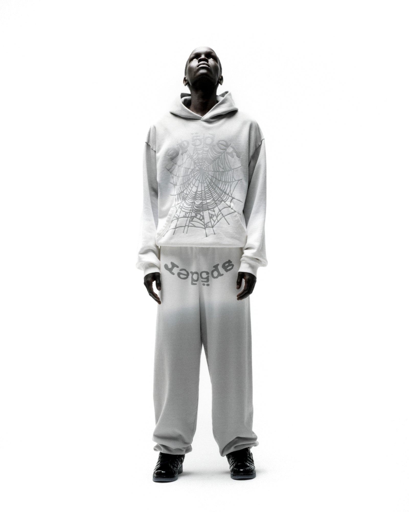 Model wearing an OG WEB OMBRE HOODIE and matching sweatpants with a spiderweb graphic.