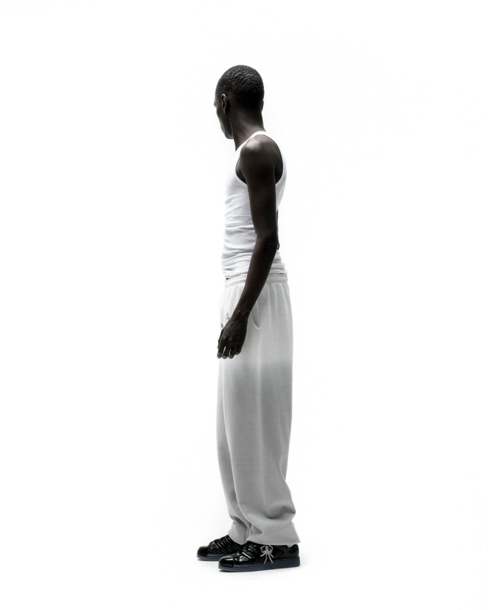 Man in white tank top and OG WEB OMBRE SWEATPANT with subtle ombre design and 'SP5DER' text.