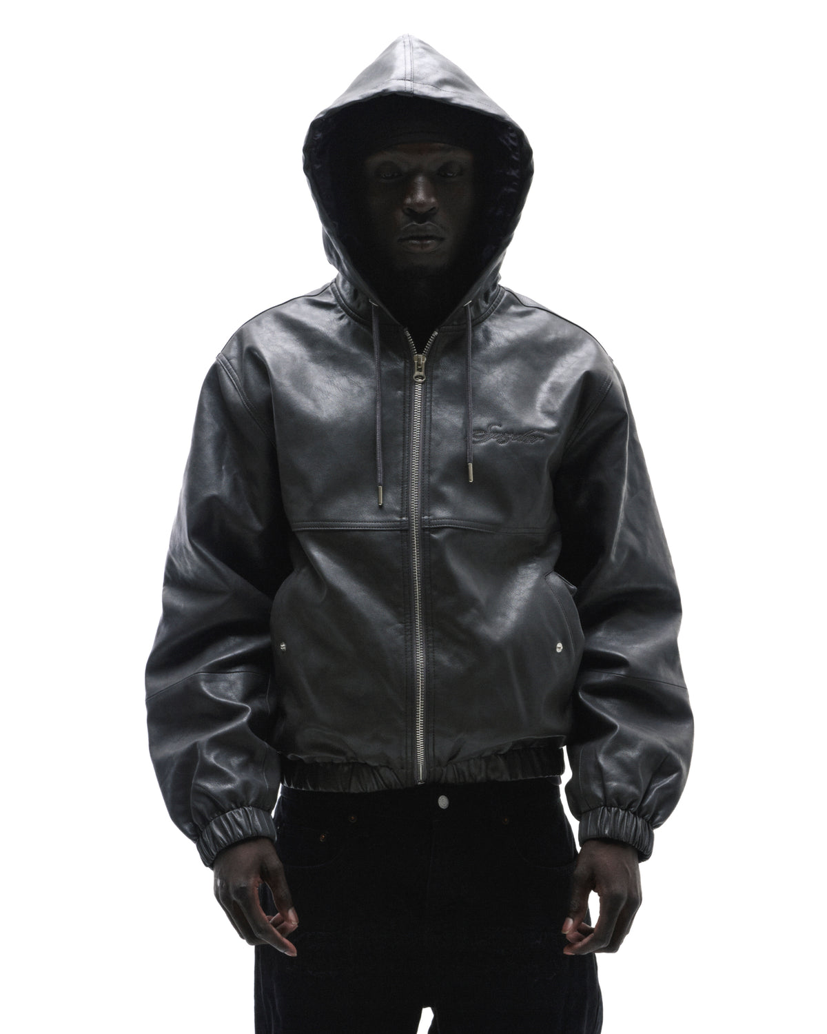 A model wearing a black leather zip-up hooded jacket with a subtle embroidered logo against a white background.