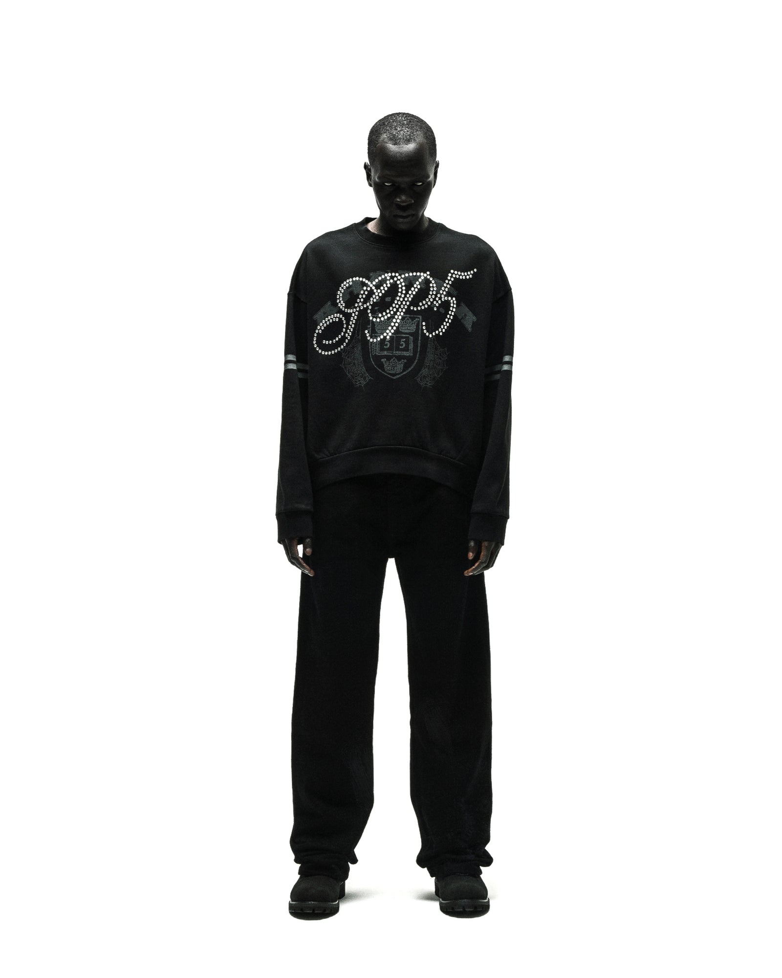 Black ARANEA CREWNECK with "SP5" rhinestone logo and striped sleeves, worn by a model.