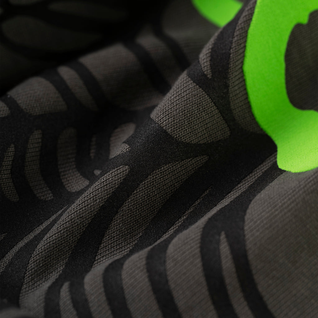 Close-up of a black cotton OG WEB V2 TEE with dark grey discharge print and bright green puff print detail.