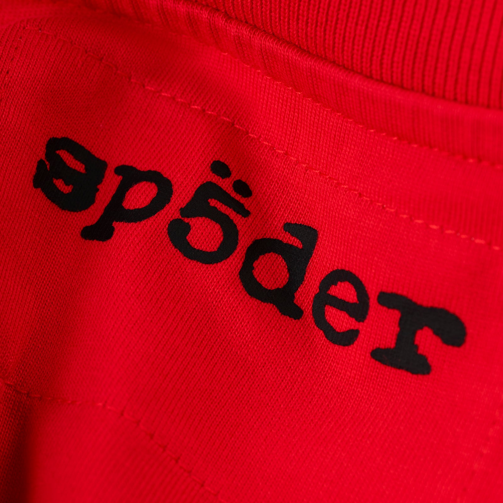 Red cotton tee with black 'SP5DER' logo on the back neck.