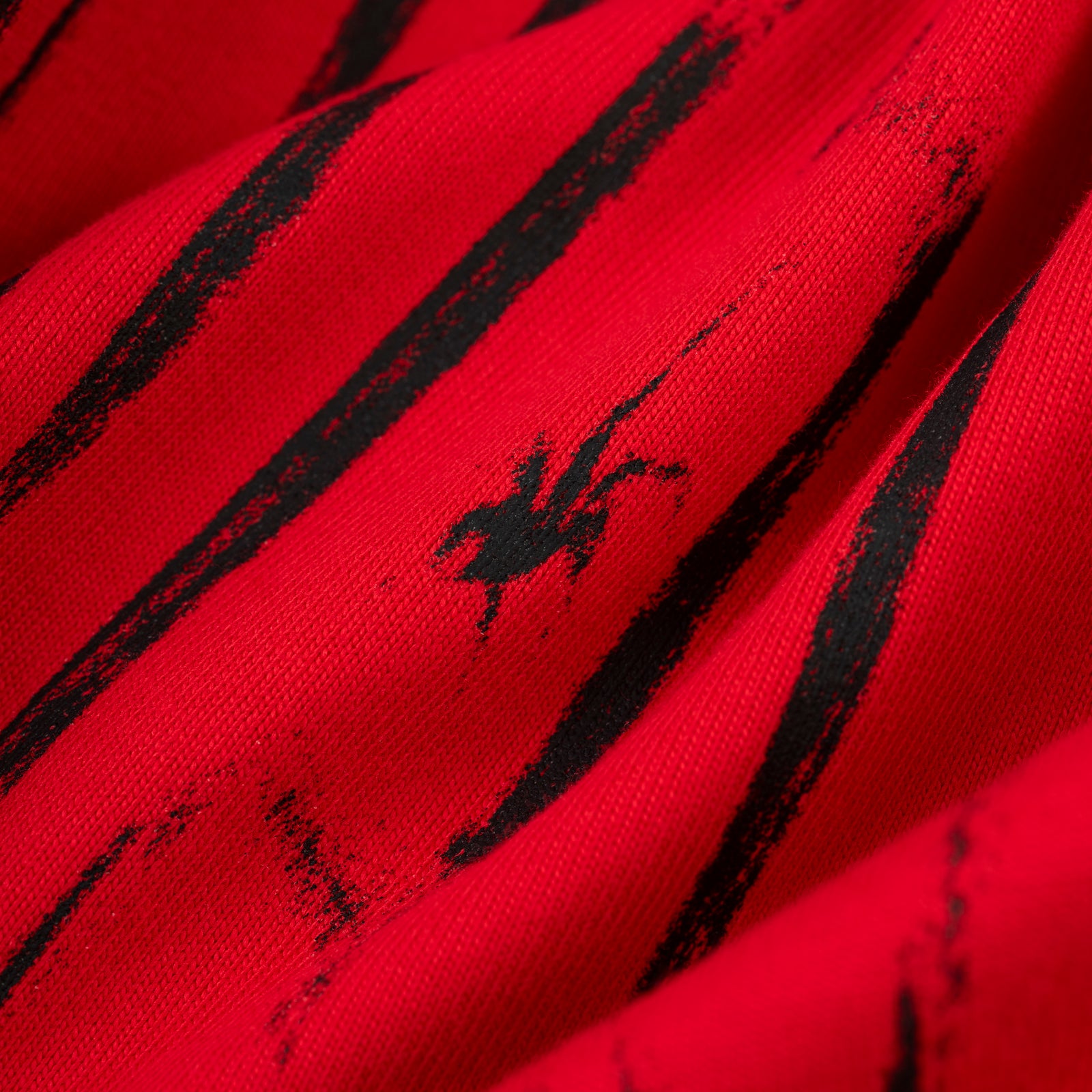 Red 100% cotton tee with black distressed stripe graphic and small black spider logo.