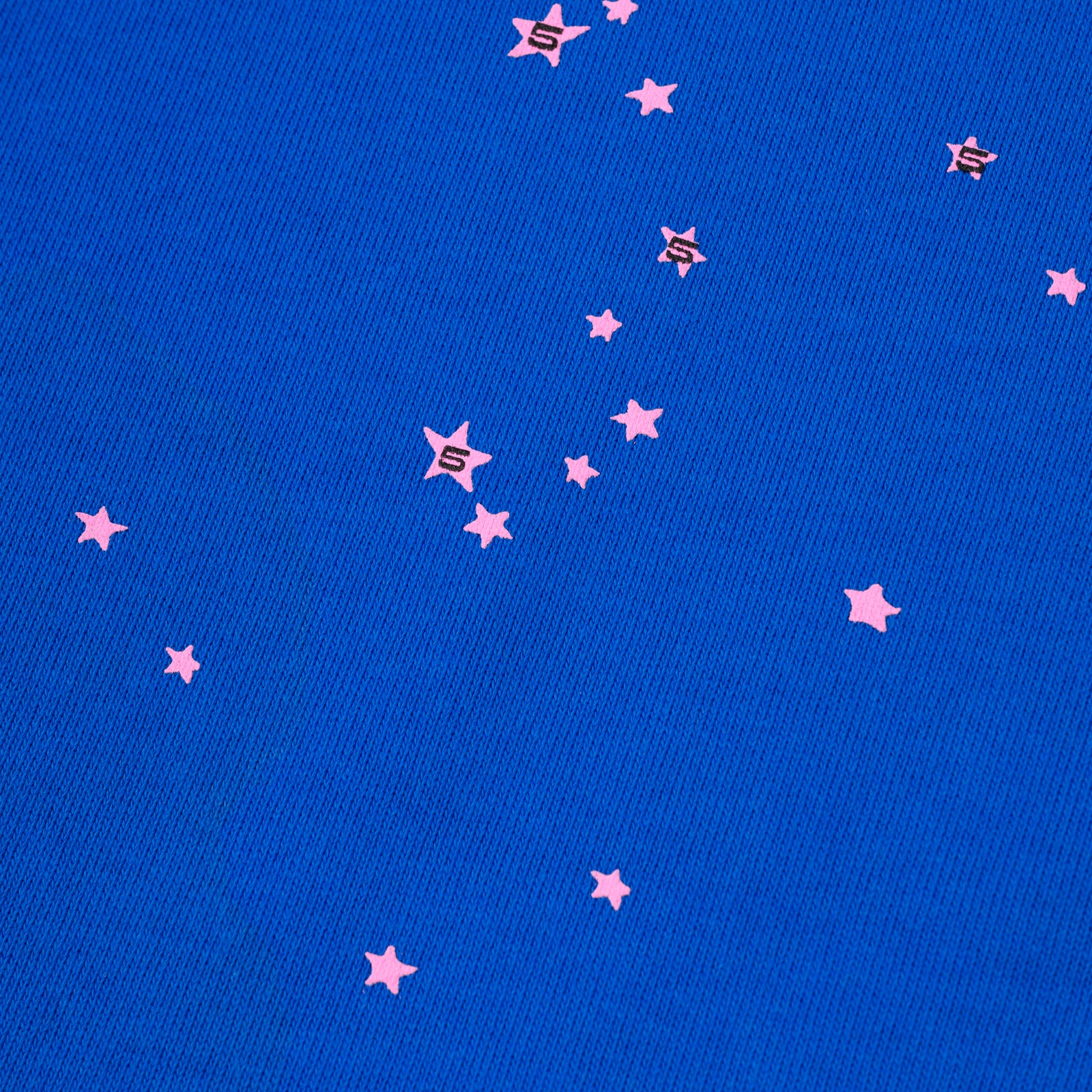 Close-up of blue cotton fleece sweatpant with scattered pink star and 'S' puff prints.