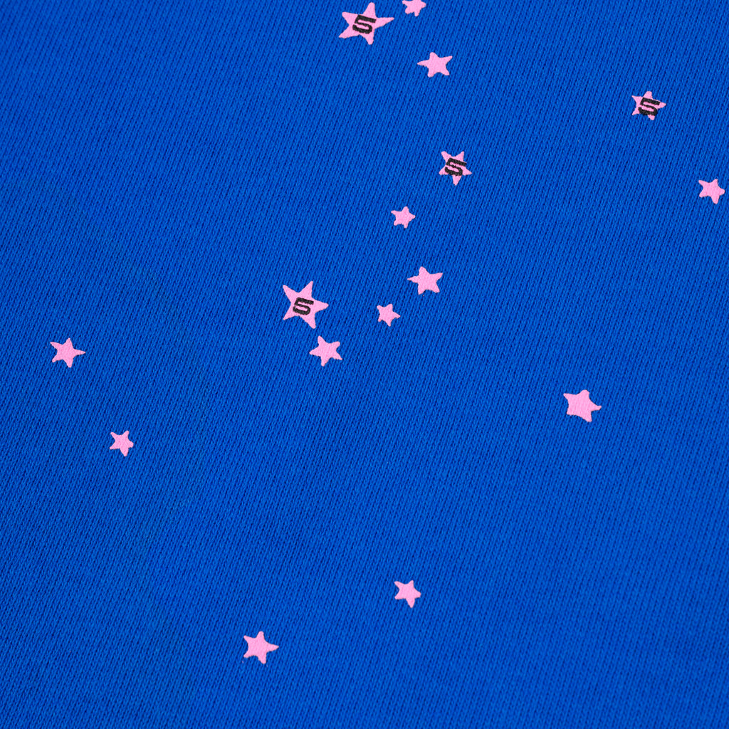 Close-up of blue cotton fleece sweatpant with scattered pink star and 'S' puff prints.