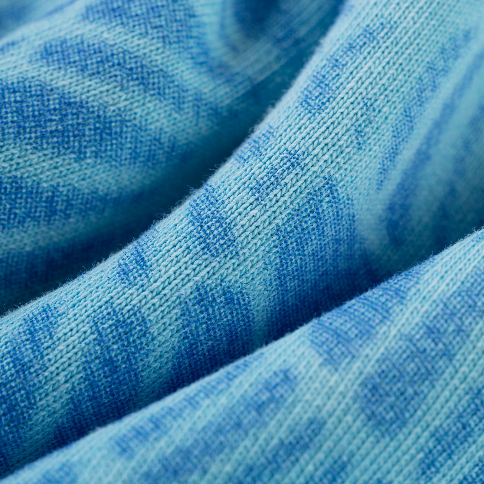 Close-up of blue 100% cotton fleece hoodie with spray web V2 print and ribbed texture.