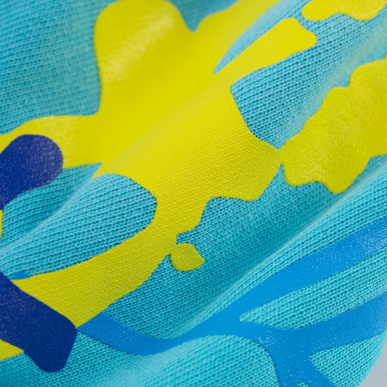 Close-up of a blue cotton fleece hoodie with yellow puff print and blue discharge print.