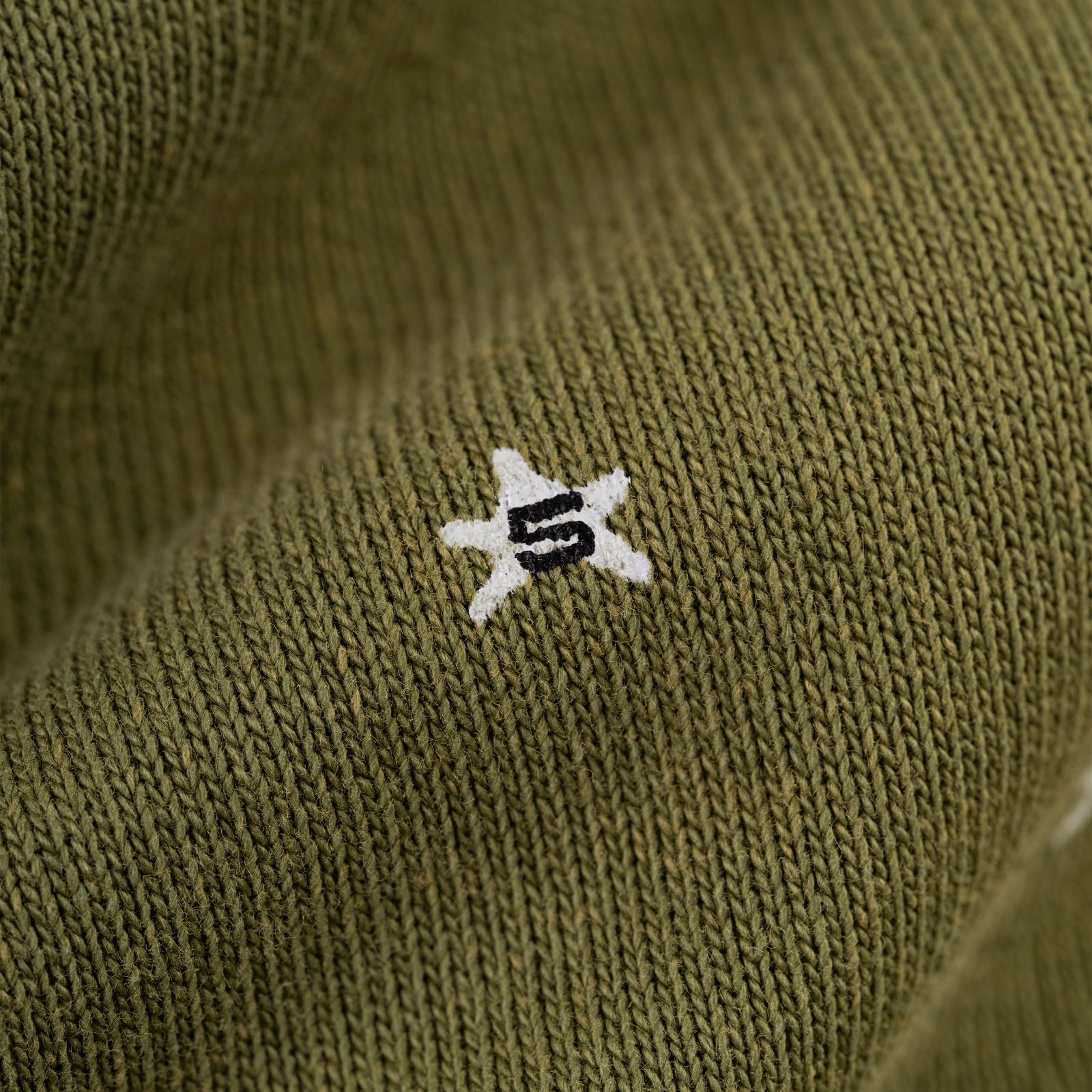 Olive green 13oz cotton fleece hoodie with white puff print star and black "S" detail.