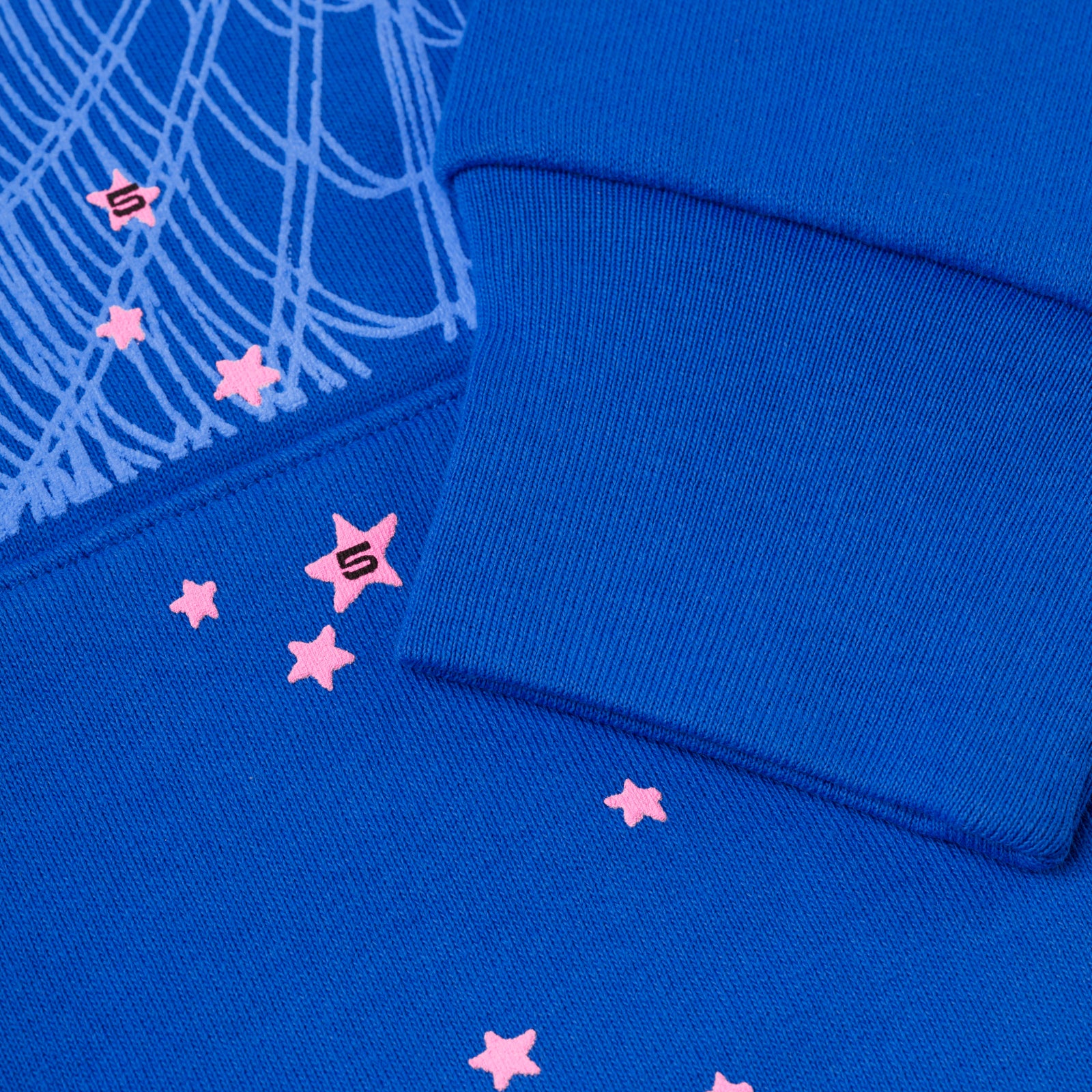 Blue fleece hoodie with pink scattered stars, "S" logo, and web print detail.