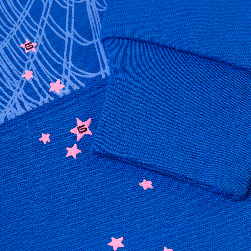 Blue fleece hoodie with pink scattered stars, "S" logo, and web print detail.