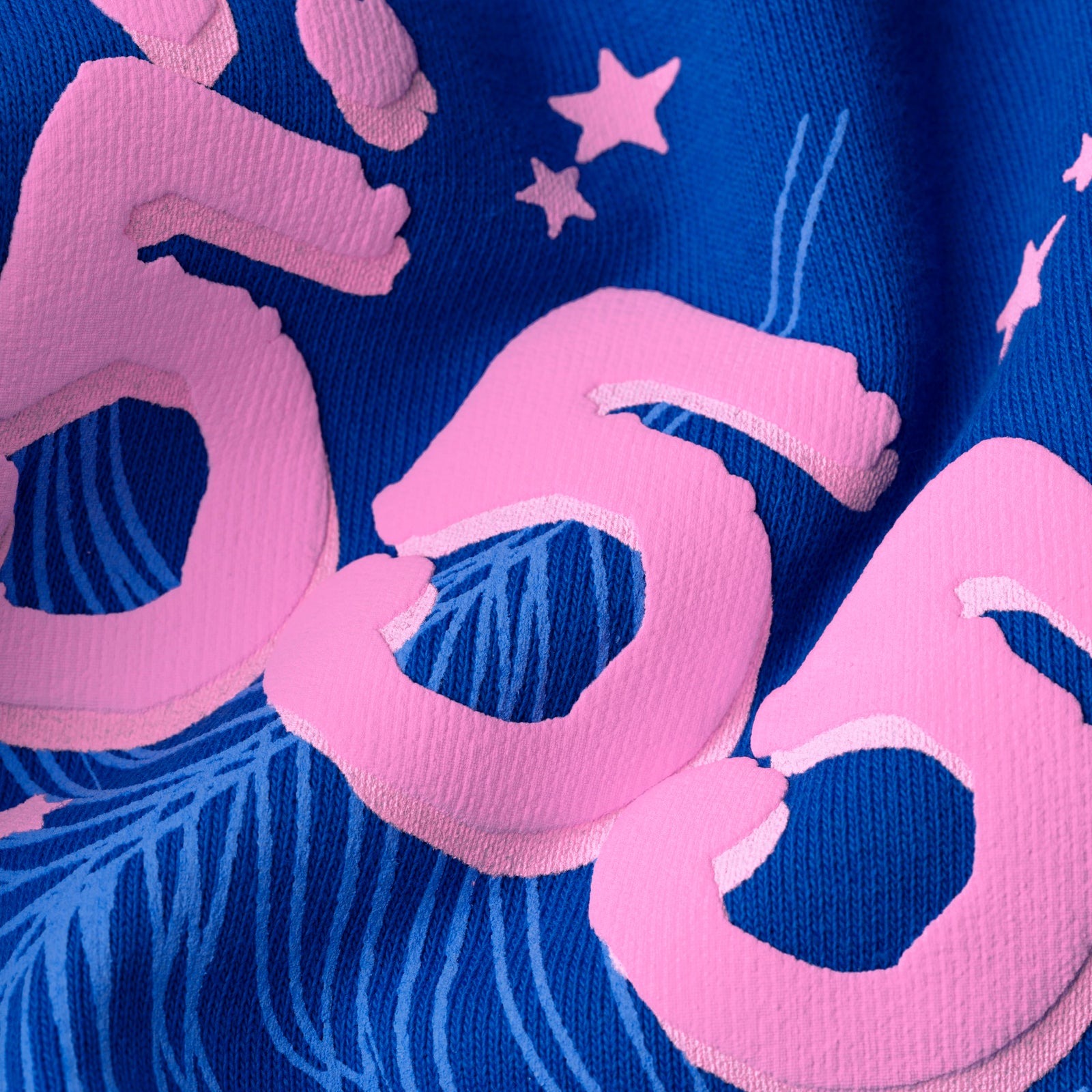 Close-up of a blue fleece hoodie with pink puff print "555" angel numbers and scattered stars.