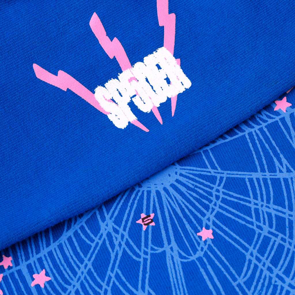 Blue fleece hoodie with pink lightning bolts, white "SP5DER" text, and a blue spiderweb print with pink stars.