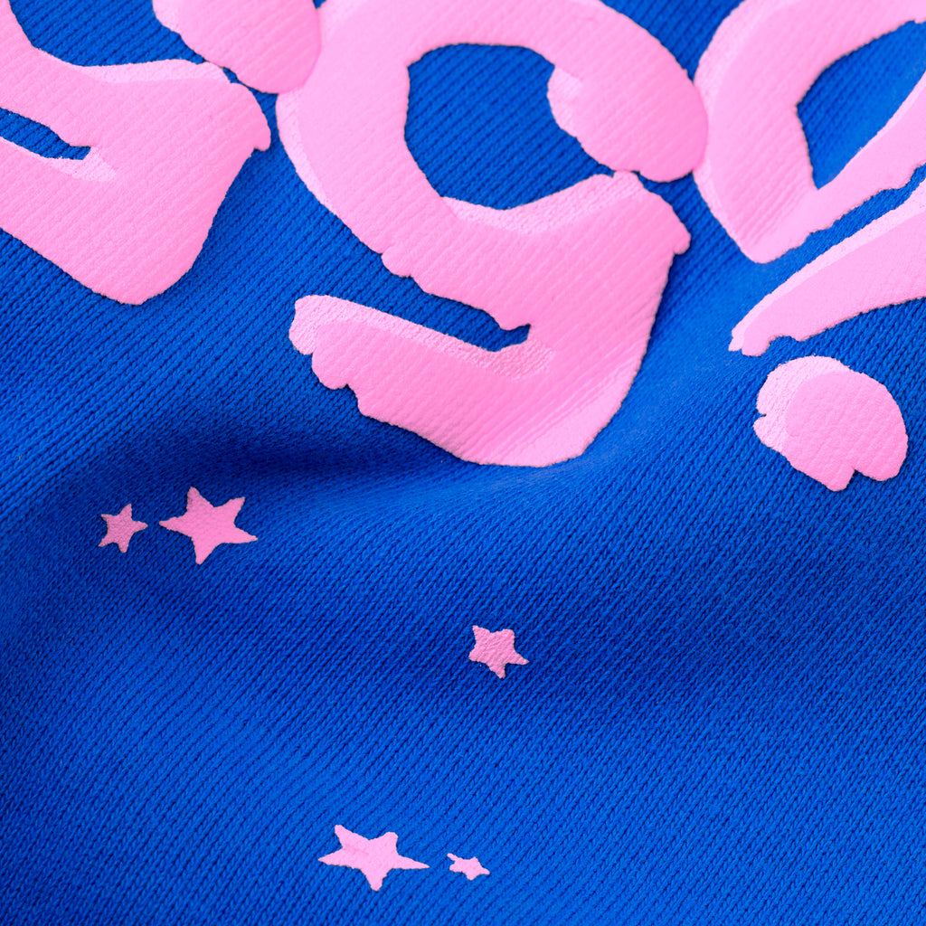 Close-up of blue cotton fleece sweatpants with pink puff print "555" and scattered stars.