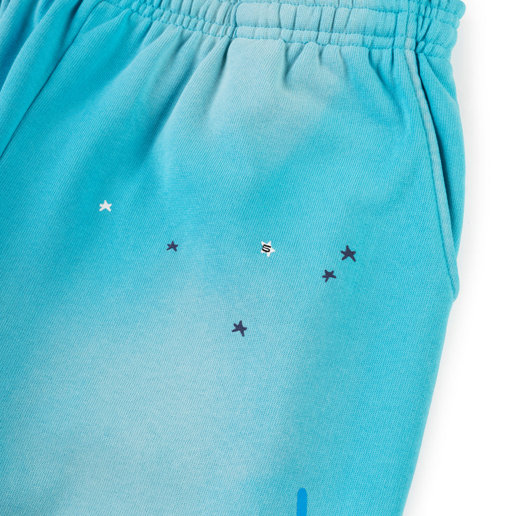 Blue cotton fleece sweatpants with SP5DER web graphic, scattered stars, elastic waist, and pocket.
