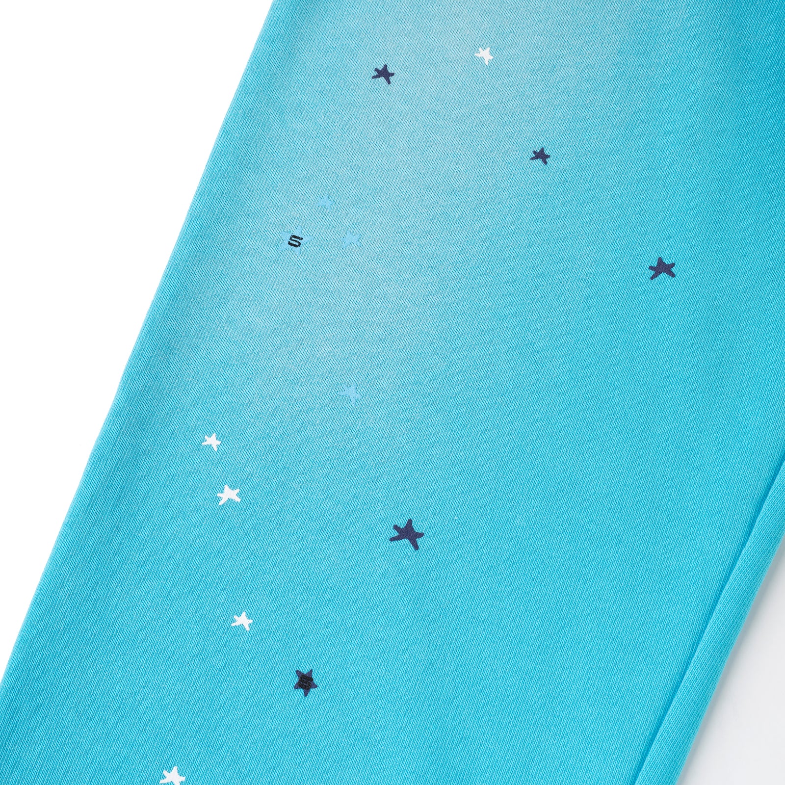 Teal cotton fleece sweatpants with scattered white and dark blue star print, and a small "S" graphic.