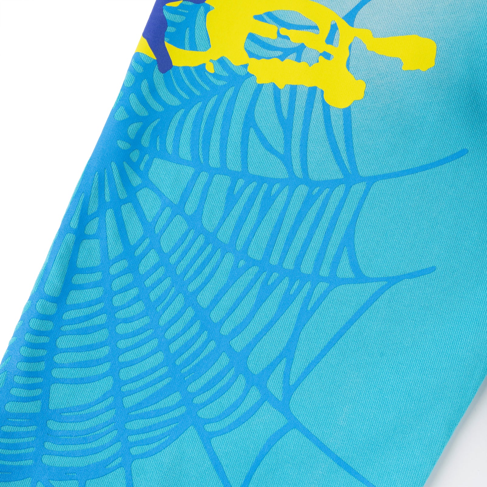 Close-up of blue cotton fleece sweatpants with a blue SP5DER web graphic and yellow puff print.