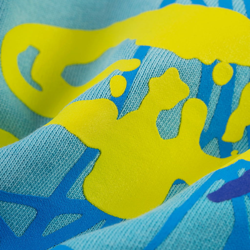 Close-up of light blue cotton fleece sweatpants with bright yellow puff print and blue discharge print.