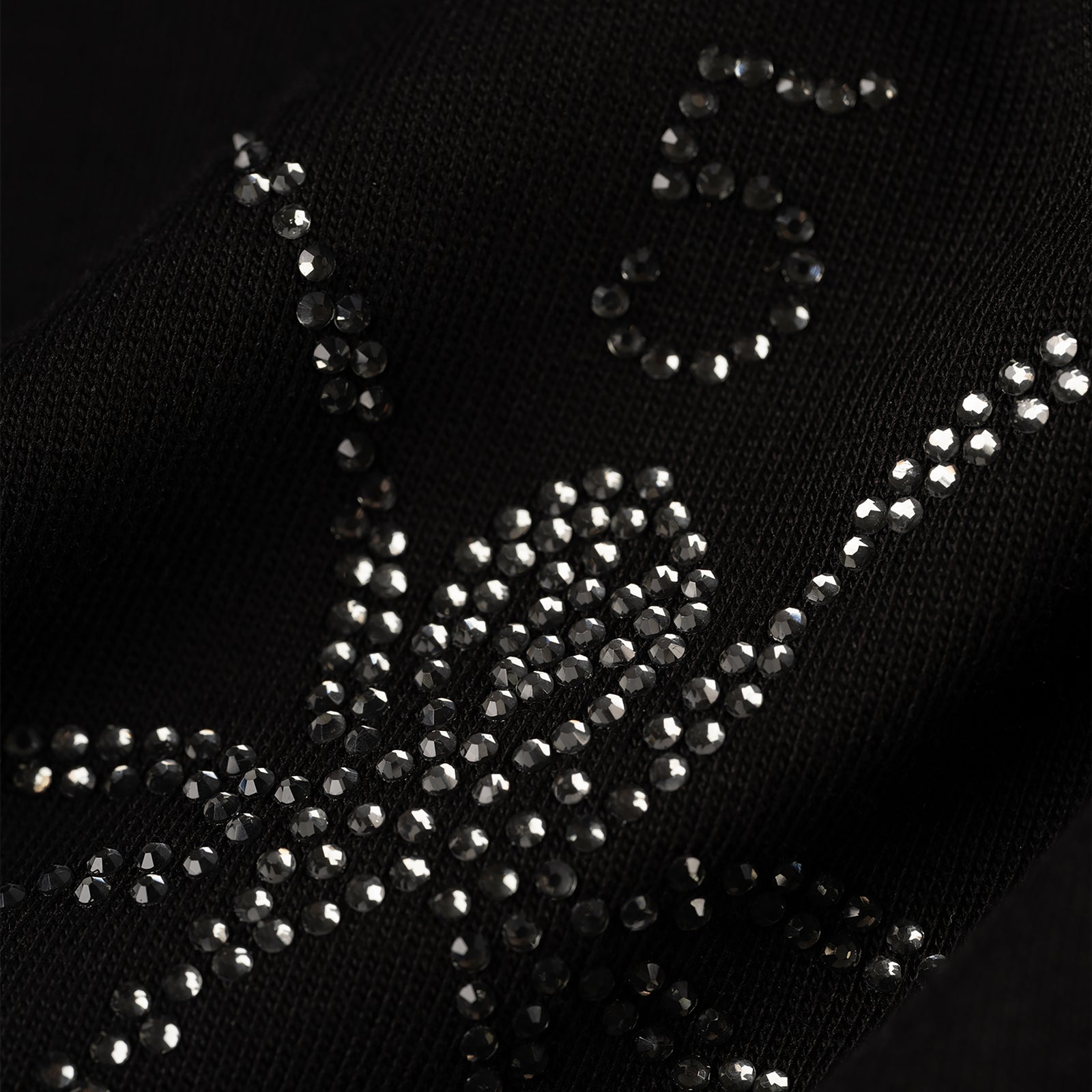 Close-up of a black 100% cotton tee with a rhinestone-embellished graphic.