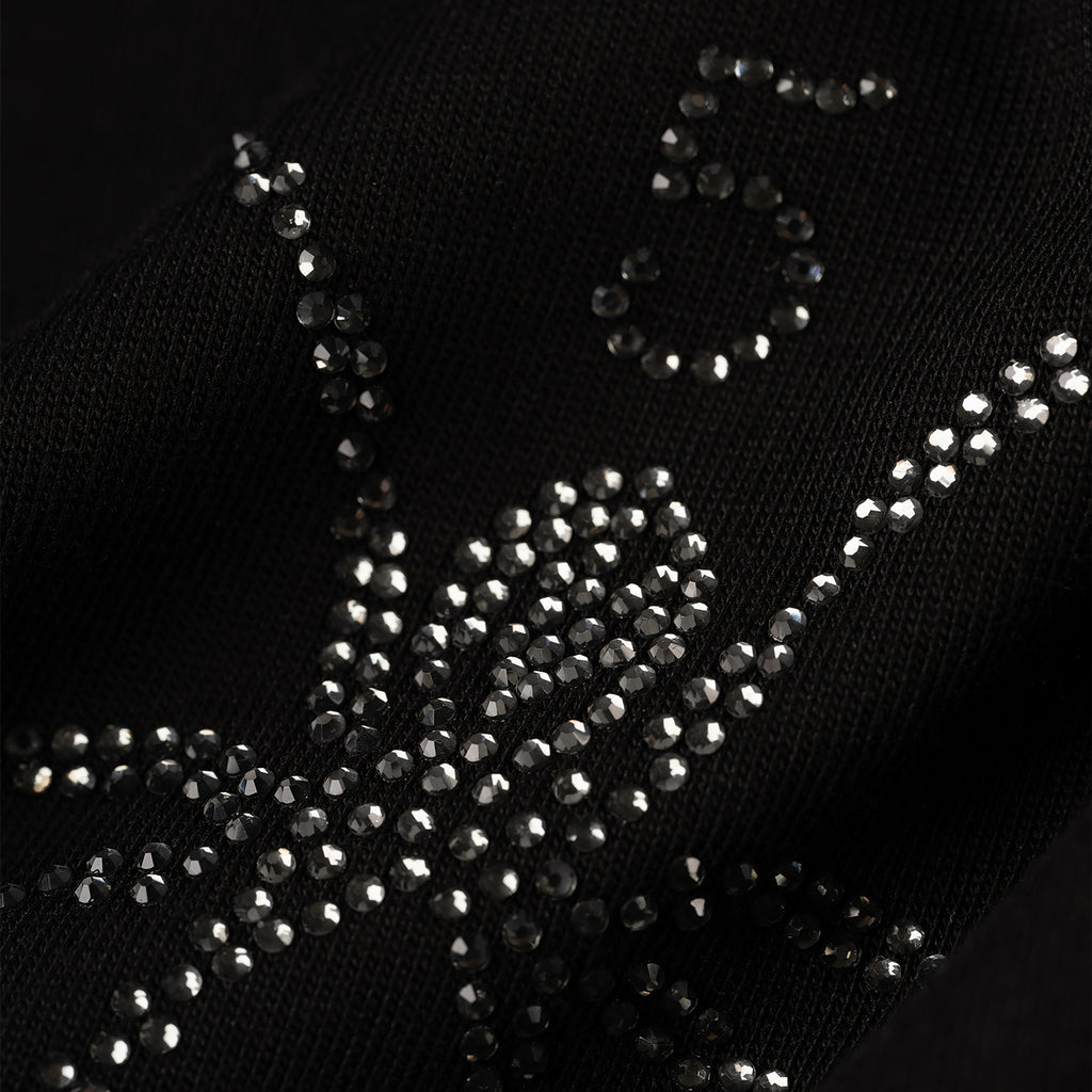 Close-up of a black 100% cotton tee with a rhinestone-embellished graphic.