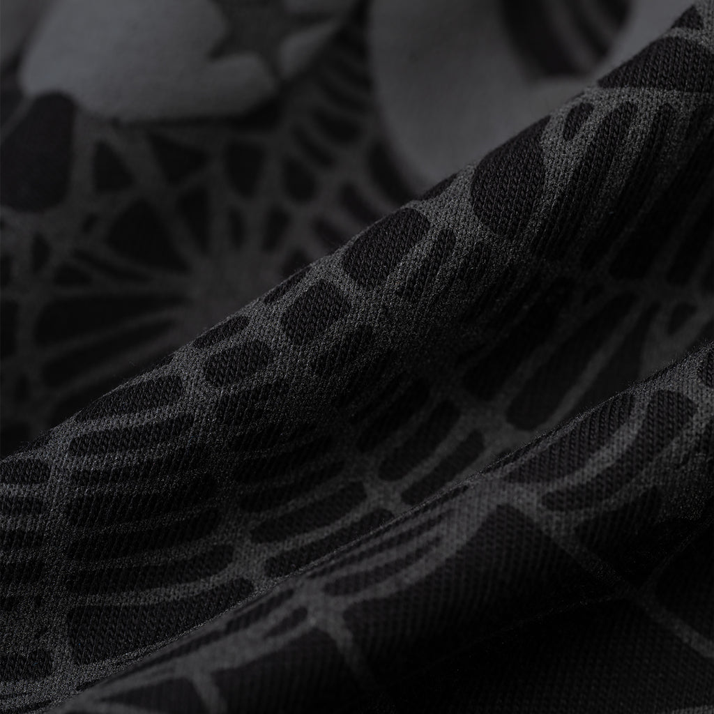 Close-up of black Phantom Souvenir Baby Tee fabric with subtle dark gray web-like pattern.