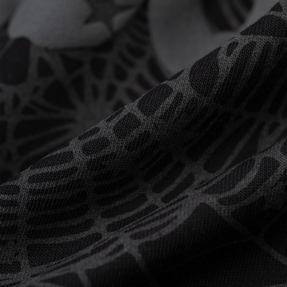Close-up of black Phantom Souvenir Men's Tee fabric with subtle dark grey web and star pattern.
