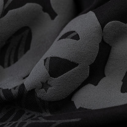 Close-up of a black men's tee with a subtle, dark gray Phantom skull and star pattern.