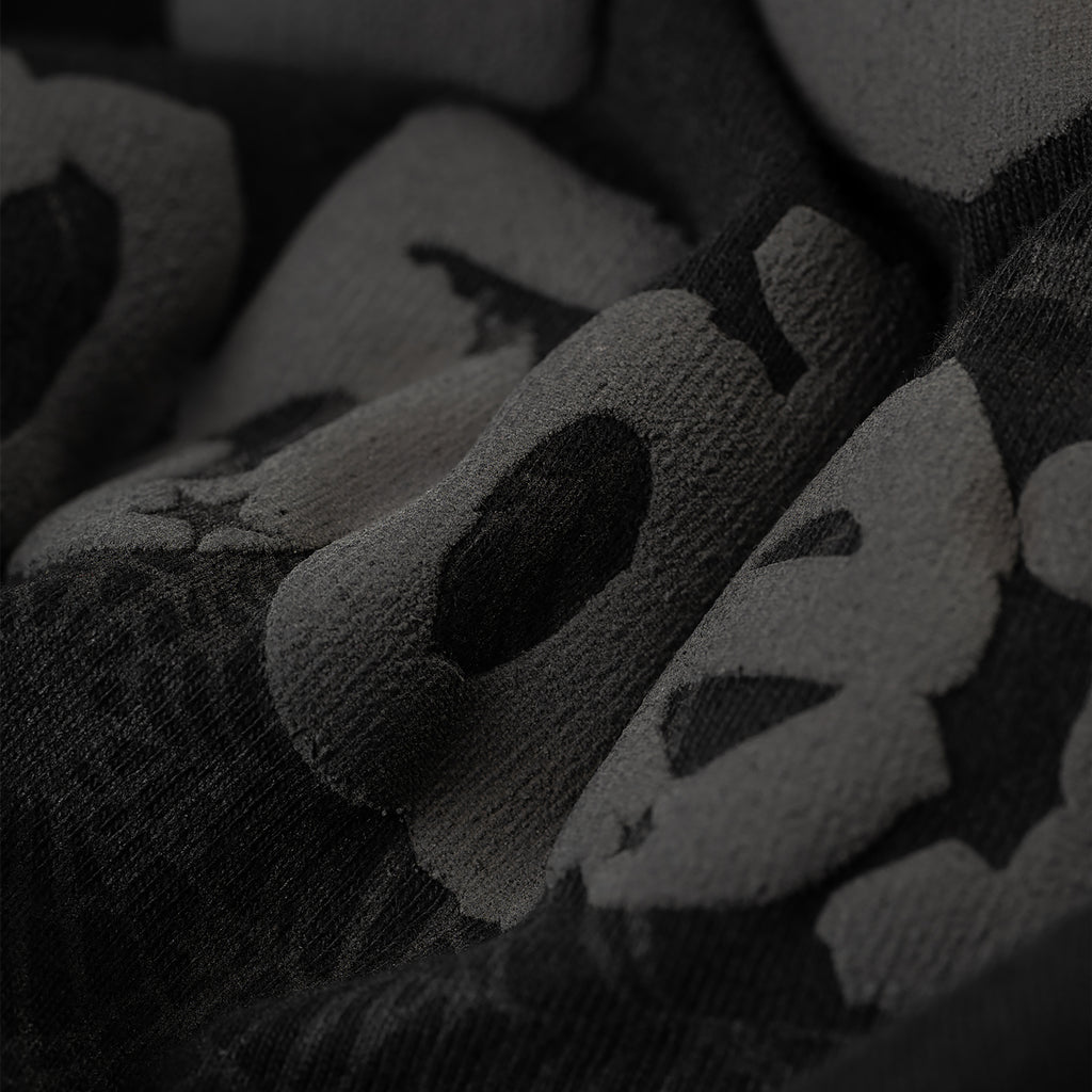 Close-up of a black Phantom Souvenir Baby Tee with subtle dark gray textured lettering.