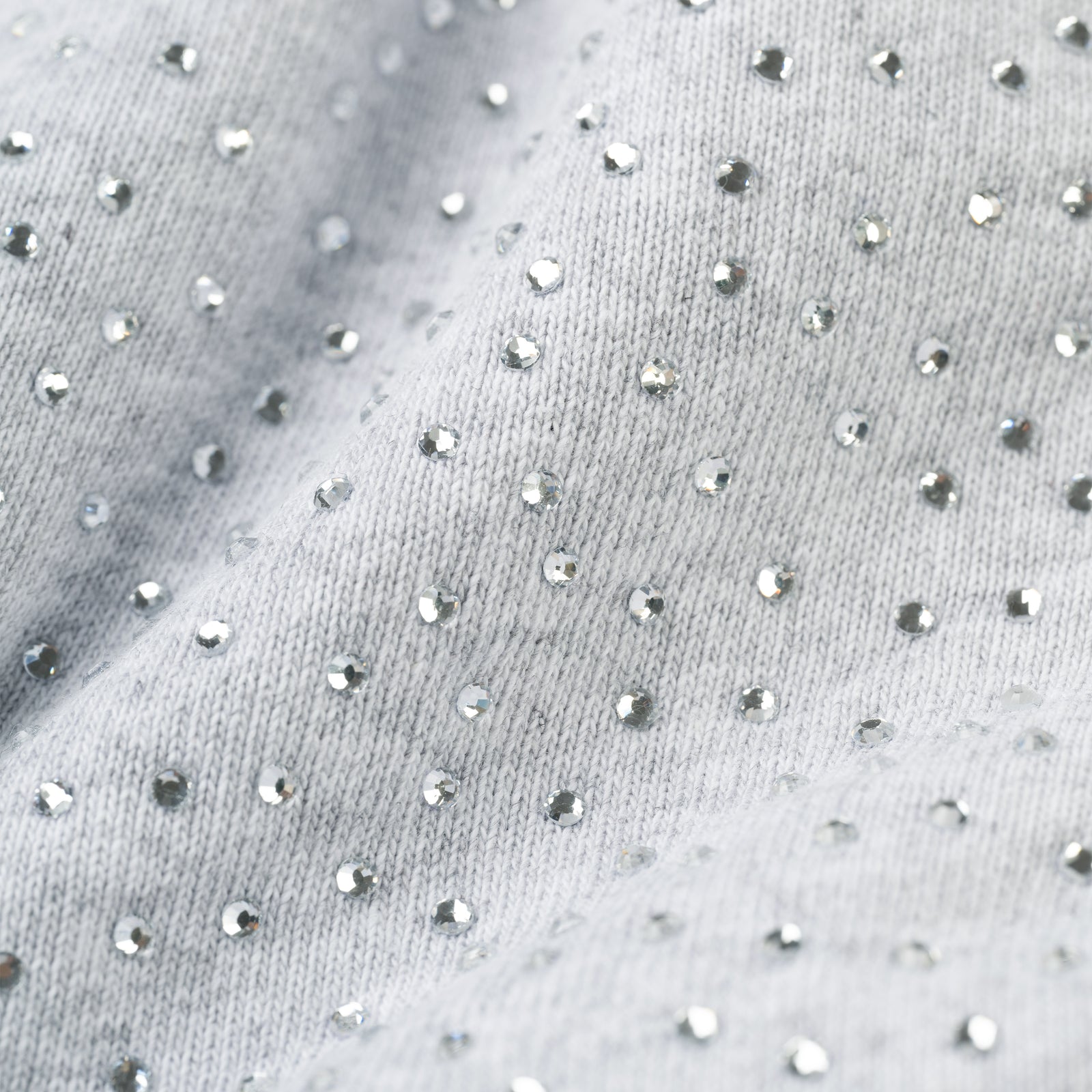 Close-up of light grey cotton fleece sweatshort fabric with all-over tonal rhinestone application.