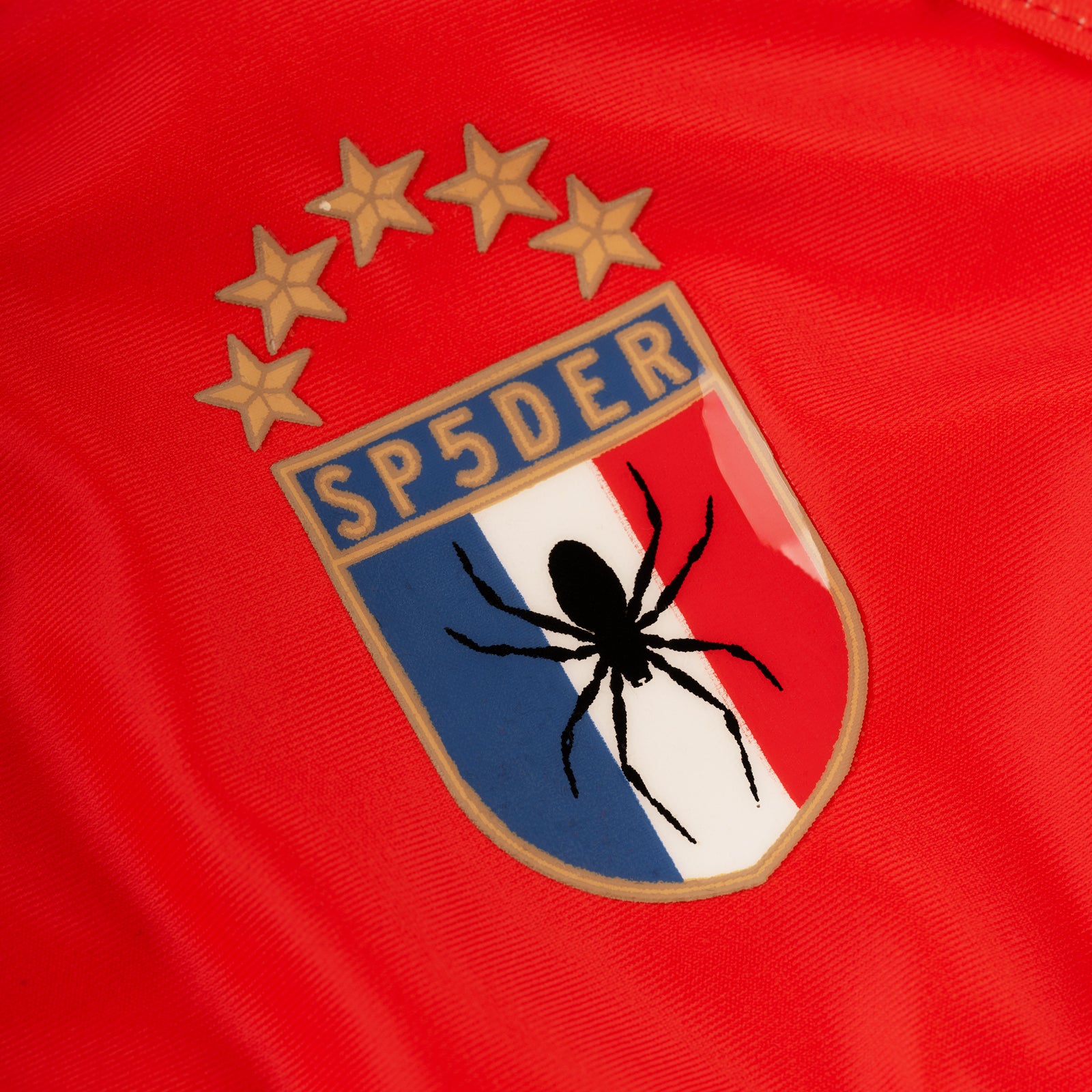 Red stretch nylon jersey bikini with SP5DER crest graphic featuring a black spider and five gold stars.