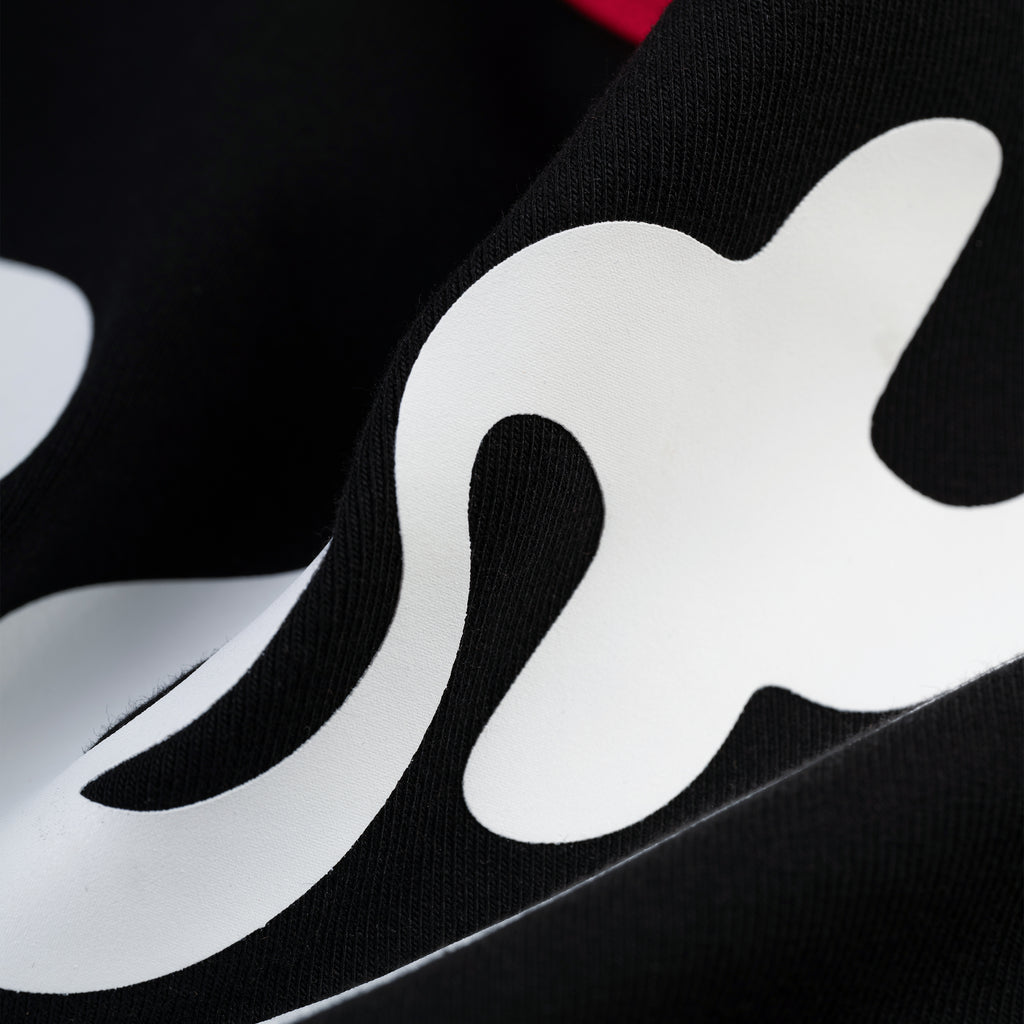 Close-up of black cotton/spandex SEX BABY TEE with white graphic print and ribbed trim.